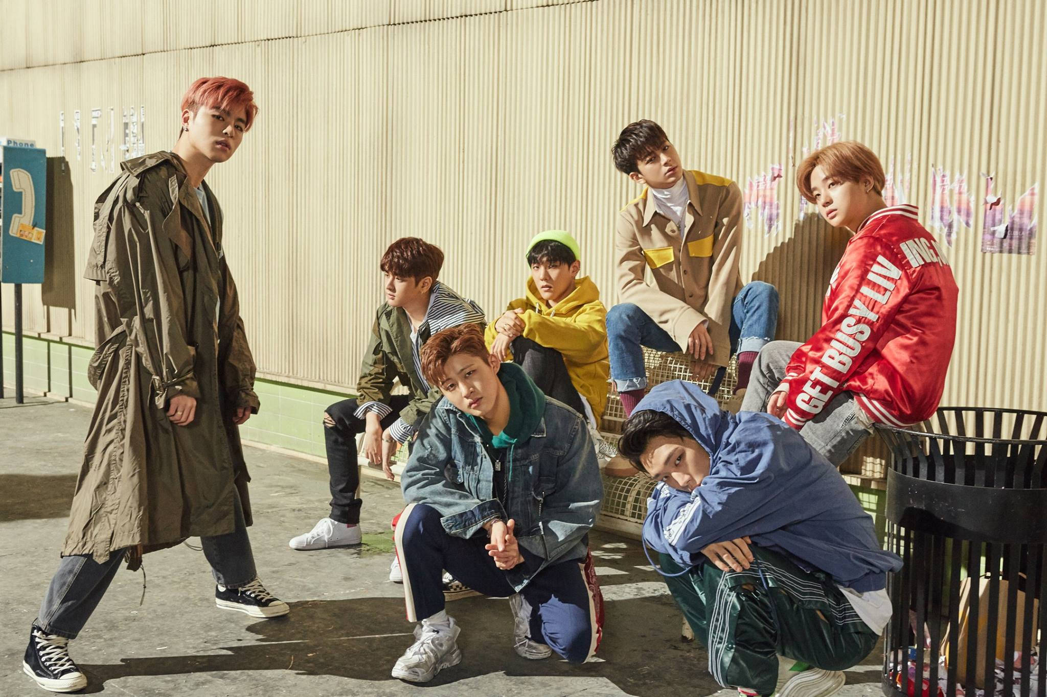 Ikon 桌布 壁紙 — 七位時尚年輕男士穿著都市街頭服飾，在明亮的日光下自信地靠在波紋金屬牆上擺姿勢。