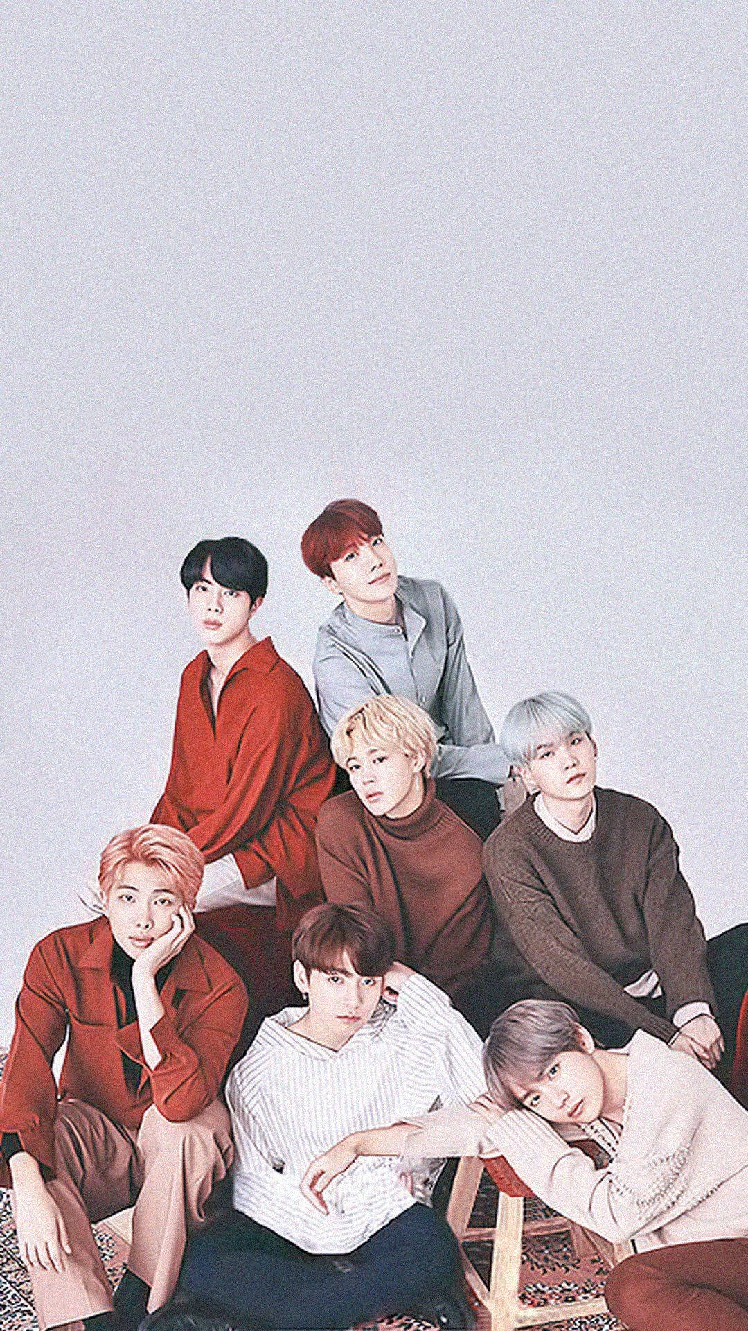 BTS 桌布 壁紙 — 七位時尚年輕男士身穿大地色系服裝，在純淺灰色背景前隨意擺姿勢。