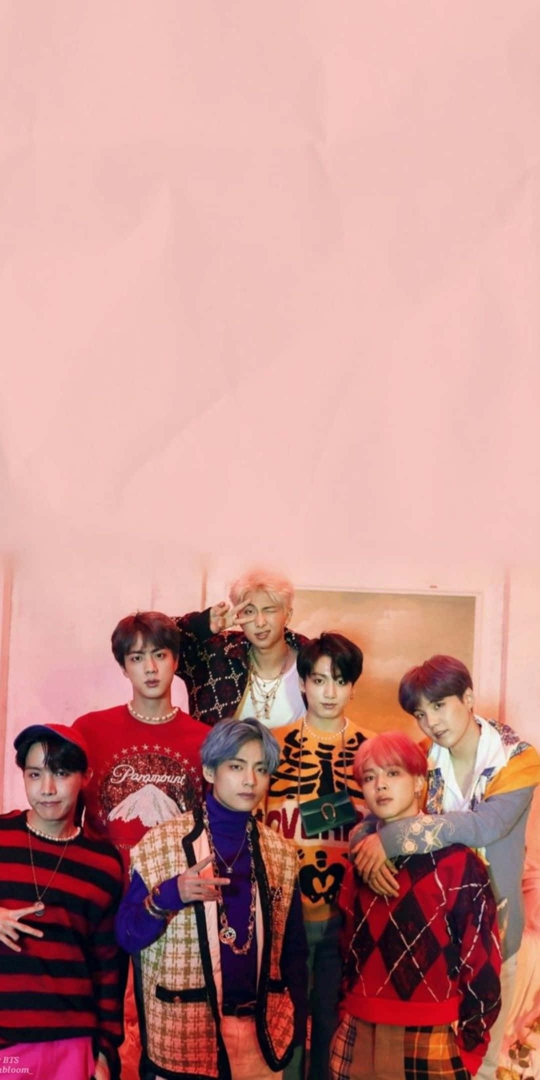 BTS 桌布 壁紙 — 七位時尚年輕男士身穿色彩繽紛的圖案服裝，在柔軟的粉紅色紋理牆前自信地擺姿勢。