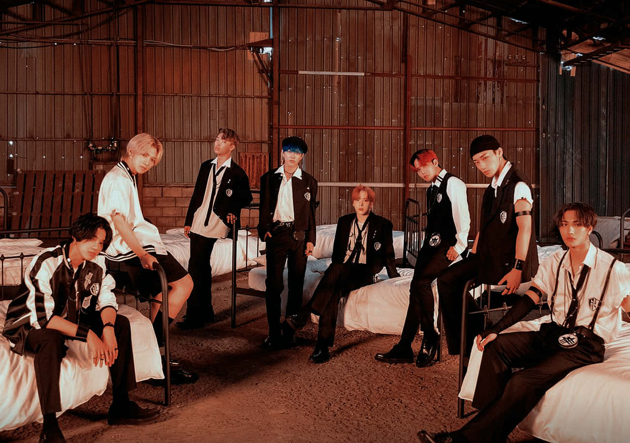 Ateez Desktop 桌布 壁紙 — 七位時尚年輕男士身穿黑白搭配服裝，在溫暖燈光的質樸倉庫中自信地躺在床上擺姿勢。