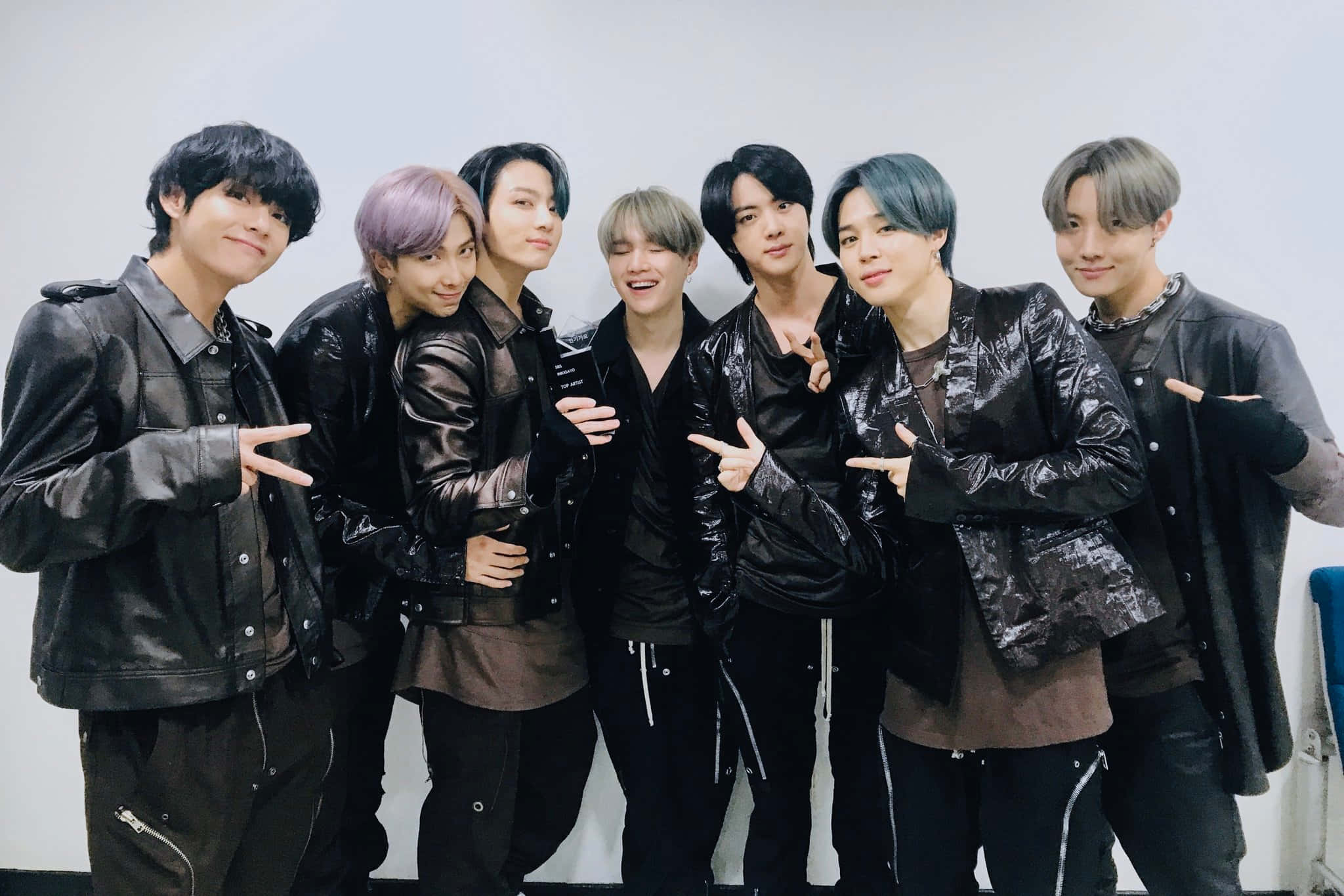 Bts Performance 桌布 壁紙 — 七位時尚年輕男士身穿黑色皮夾克，在純白牆前自信擺出俏皮手勢。