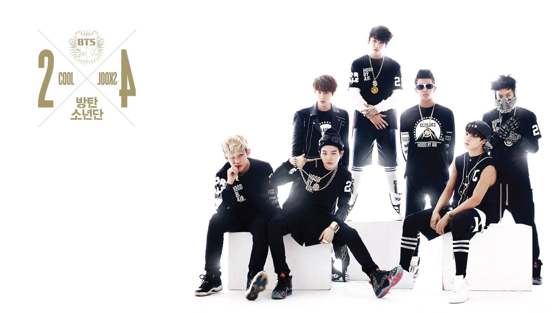 BTS 桌布 壁紙 — 七位時尚年輕男士身穿黑色街頭服飾，自信地站在白色方塊上，背景為純白色。