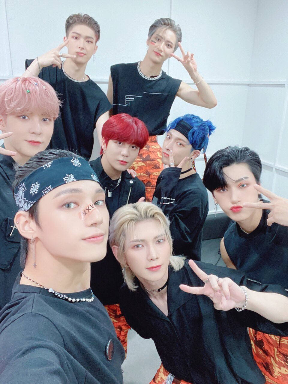 ateez 桌布 壁紙 — 七位時尚年輕男子，擁有色彩繽紛的頭髮和潮流配飾，在明亮的室內環境中一起擺出和平手勢。