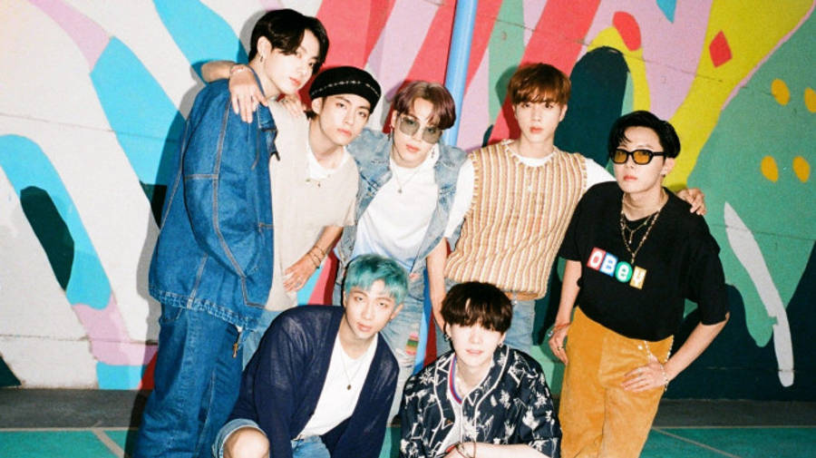 BTS 桌布 壁紙 — 七位時尚年輕男子在充滿活力的塗鴉牆前自信擺姿勢，牆上有大膽的抽象圖案。