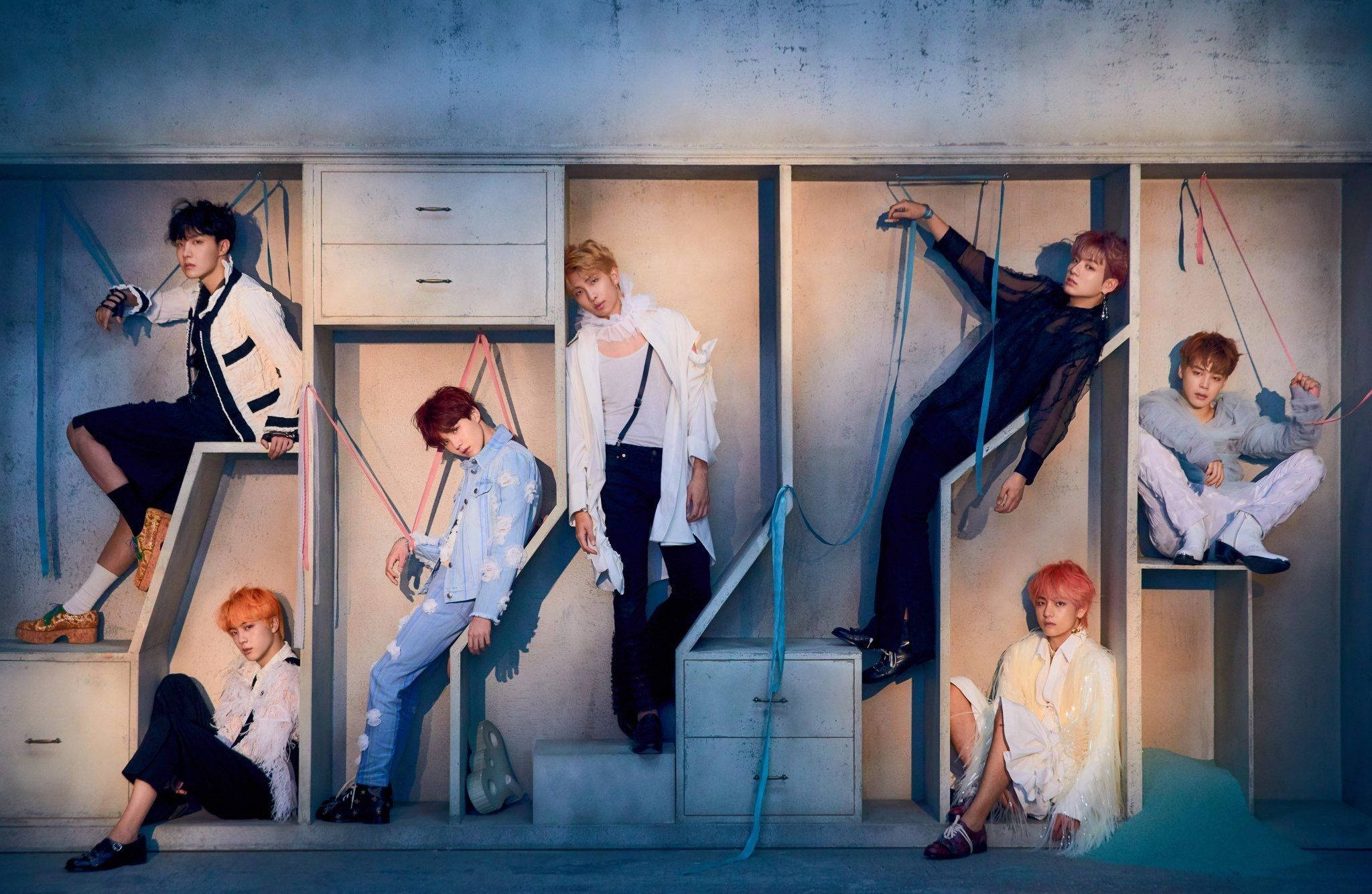 BTS 筆電 桌布 壁紙 — 七位時尚年輕男子在現代混凝土樓梯結構中動態擺姿勢，配有彩色繩索和柔和燈光。