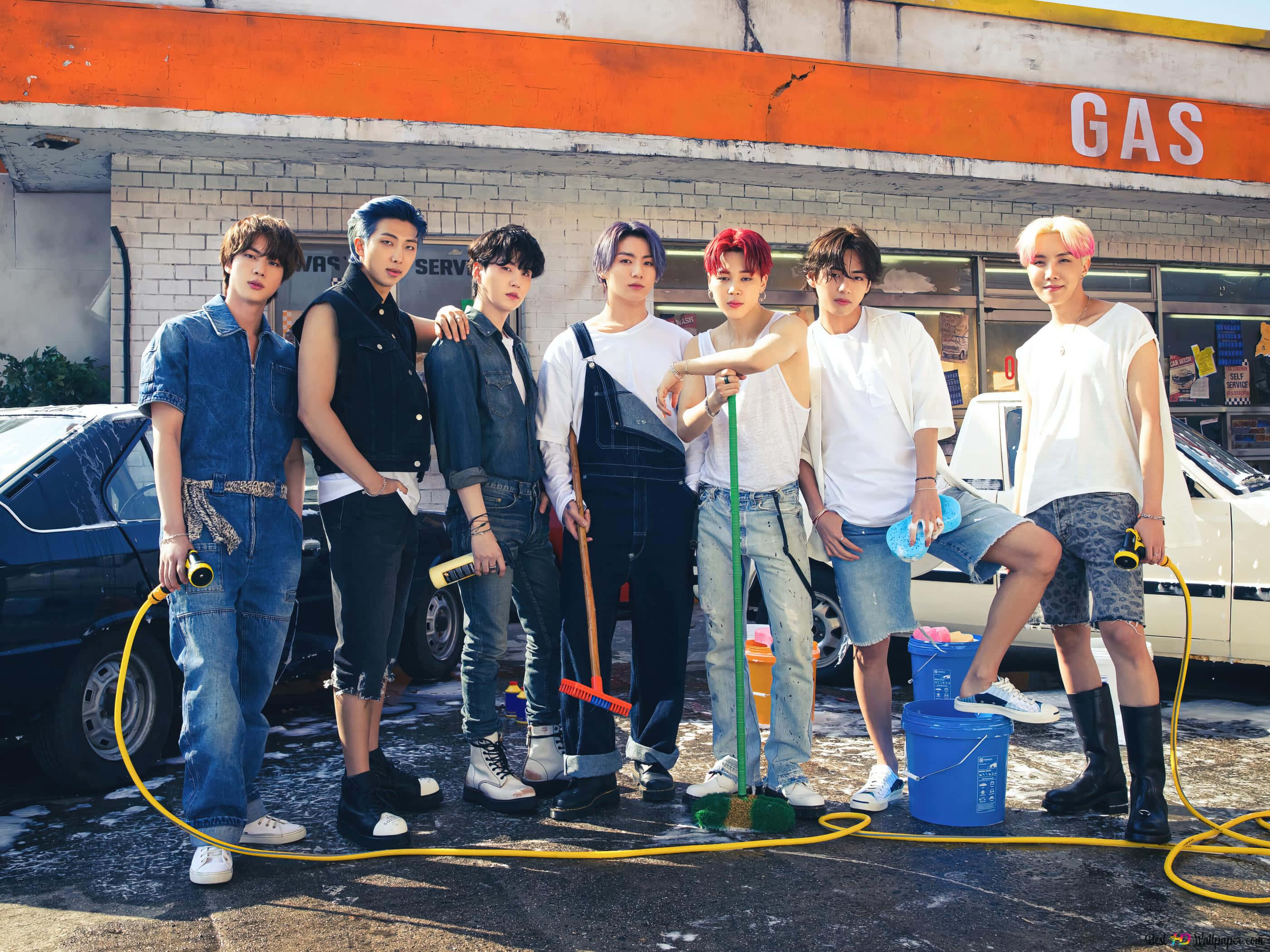 BTS 桌布 壁紙 — 七位時尚年輕男子在陽光普照的加油站洗車場自信地擺姿勢，手持水管和水桶。