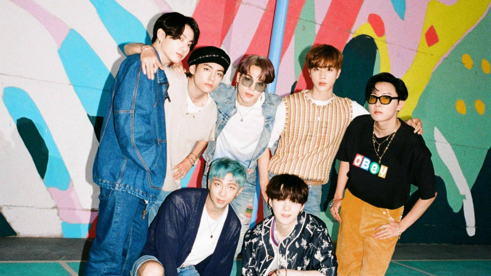 bts 2021 desktop 桌布 壁紙 — 七位時尚年輕男子自信地擺姿勢，背景是一面充滿活力、帶有鮮豔大膽形狀的抽象塗鴉牆。