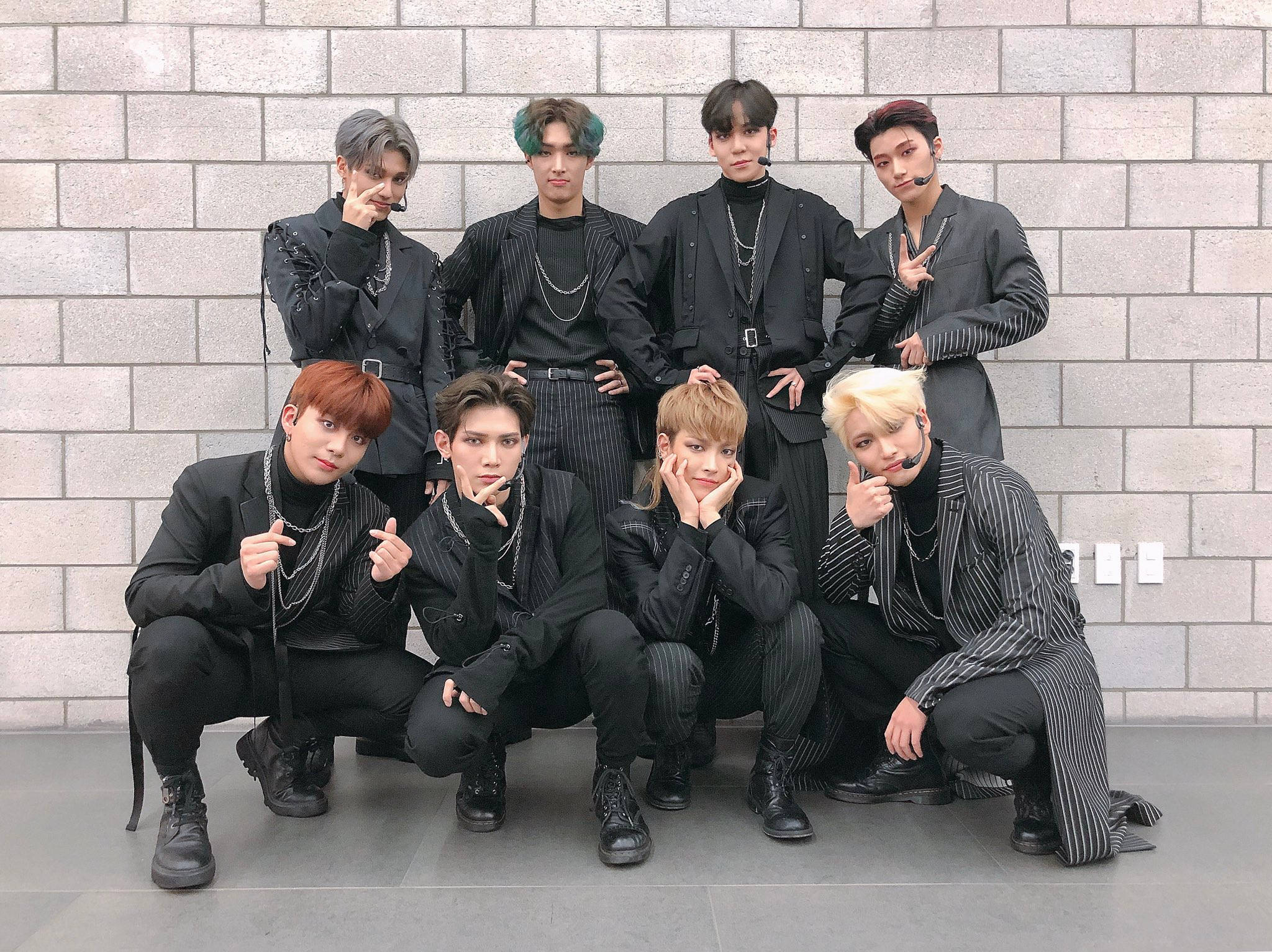 ateez 桌布 壁紙 — 七位時尚年輕男子身穿黑色細條紋套裝，在灰色磚牆前自信擺姿勢。