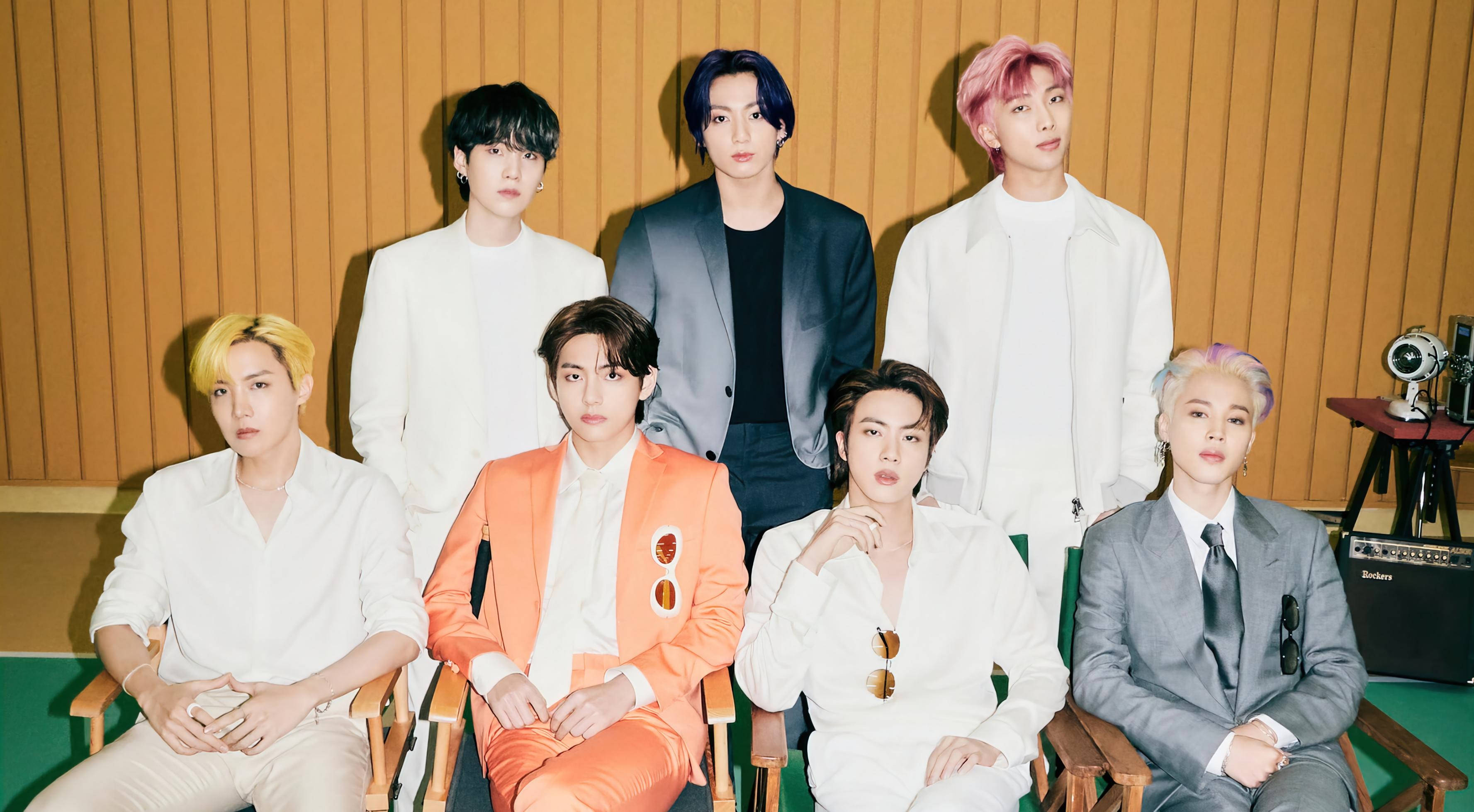 bts 2021 desktop 桌布 壁紙 — 七位時尚男士，頭髮色彩繽紛，自信地穿著西裝，靠著溫暖的木鑲板牆擺姿勢。