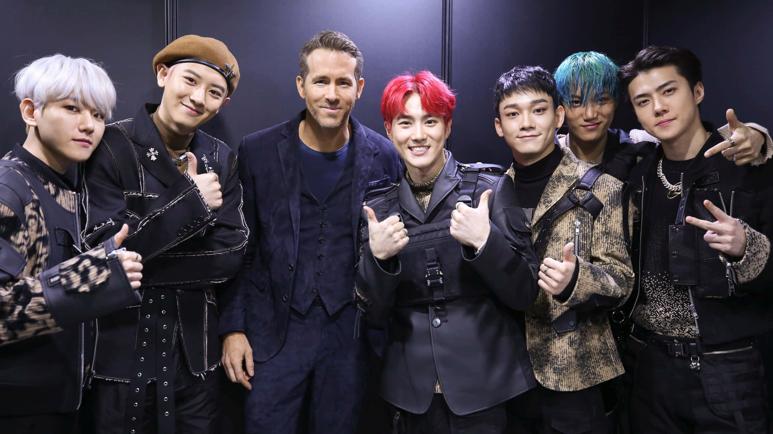 EXO 桌布 壁紙 — 七位時尚男士以鮮豔的髮色，自信地穿著深色外套，在黑色背景前擺姿勢。