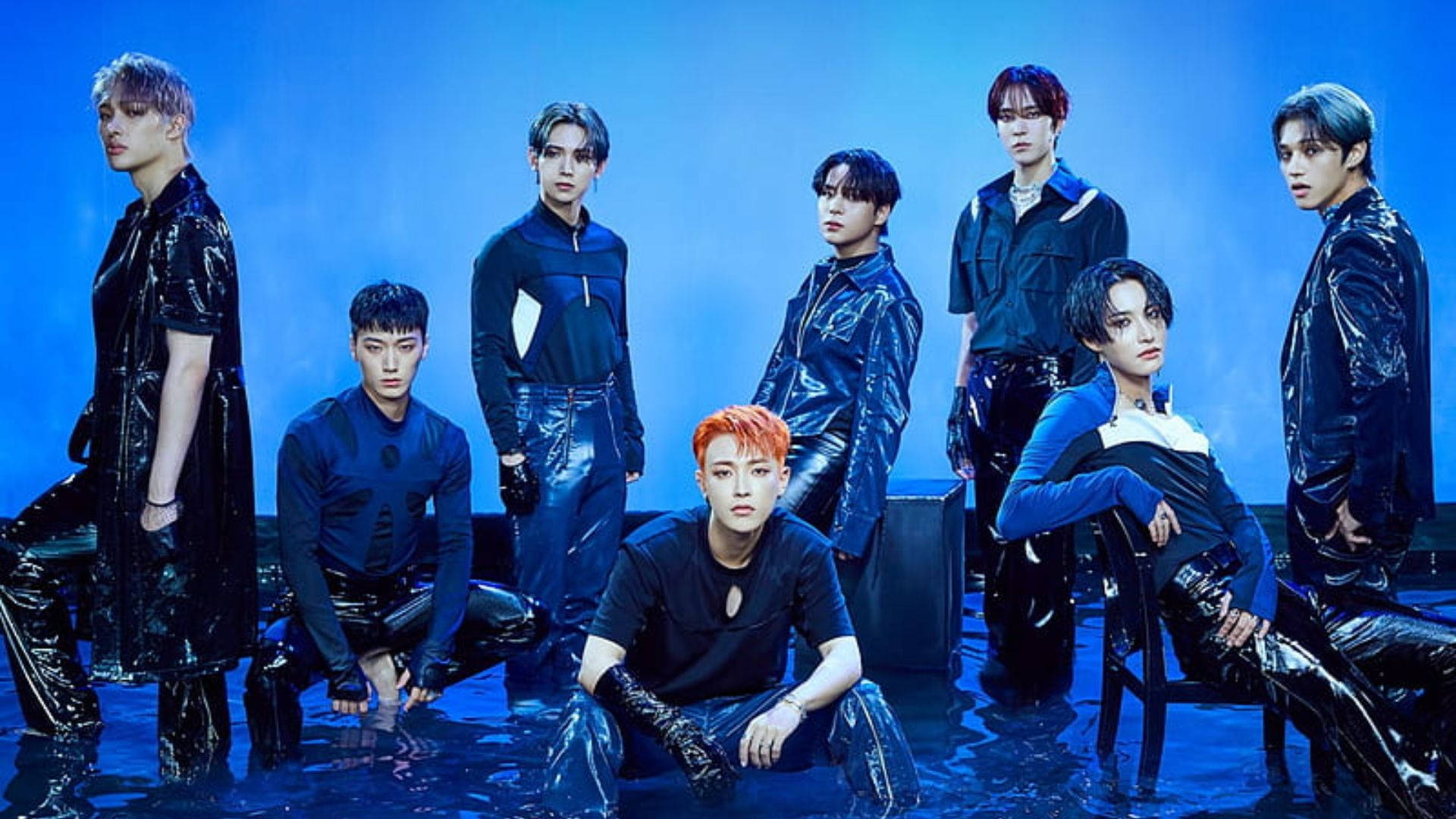 Ateez Desktop 桌布 壁紙 — 七位時尚男士身穿亮黑色服裝，在帶有濕地效果的反射藍光攝影棚中戲劇性地擺姿勢。