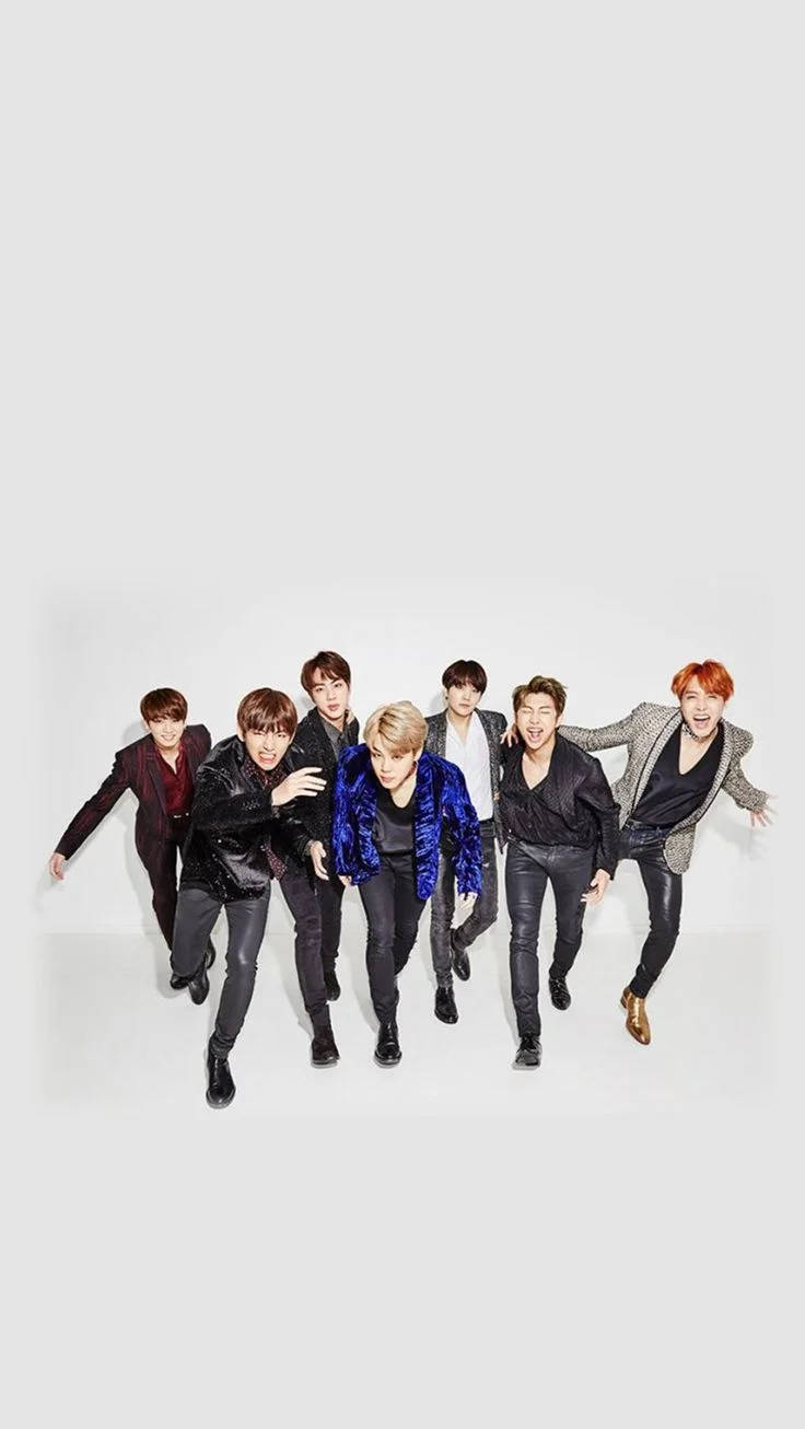bts iPhone 桌布 壁紙 — 七位時尚男士身穿深色西裝和醒目外套，在純白背景前擺出動感姿勢。