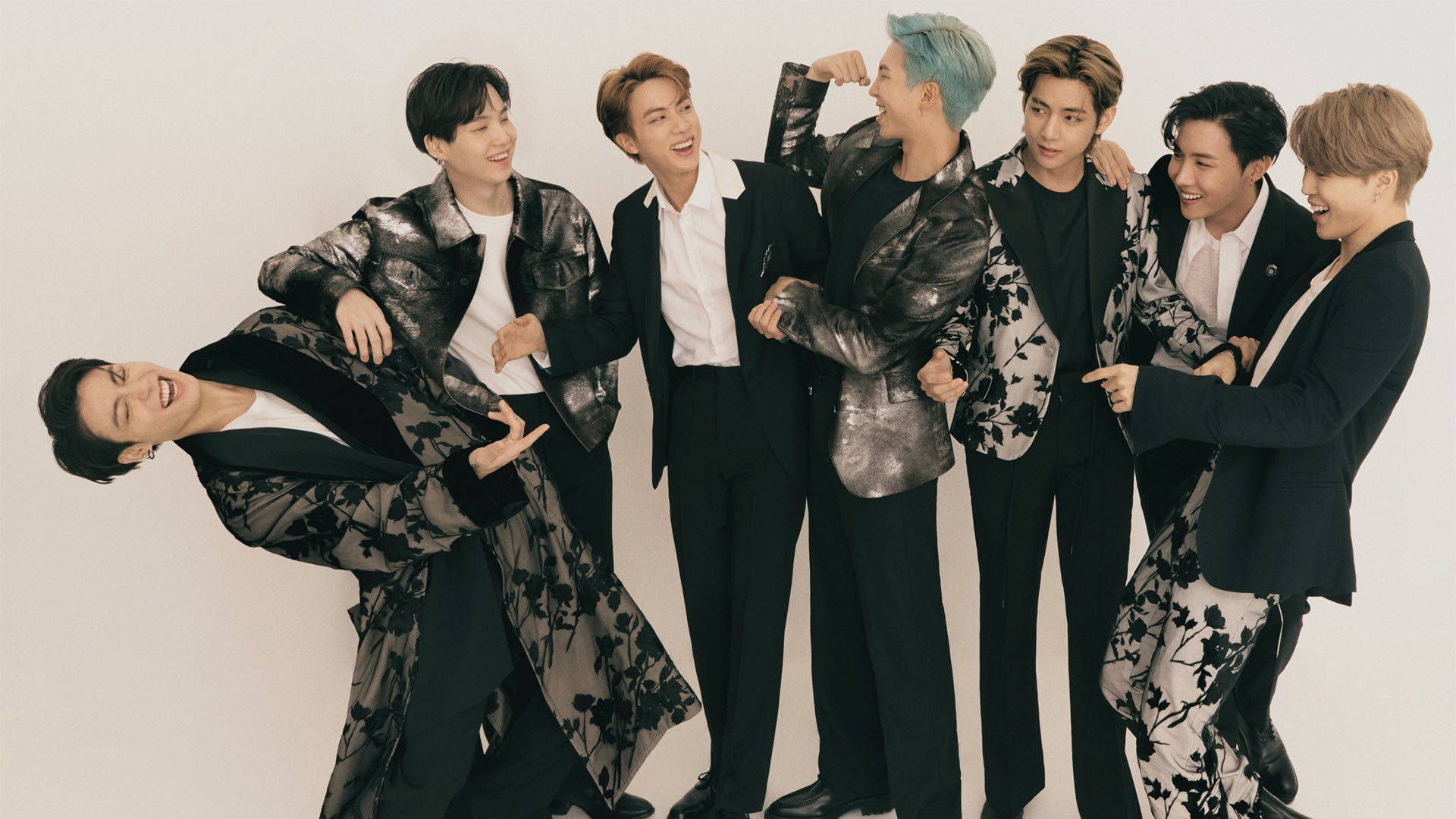 BTS 2021 桌布 壁紙 — 七位時尚男士身穿黑色花卉圖案外套，在純白背景前笑著並擺出俏皮姿勢。