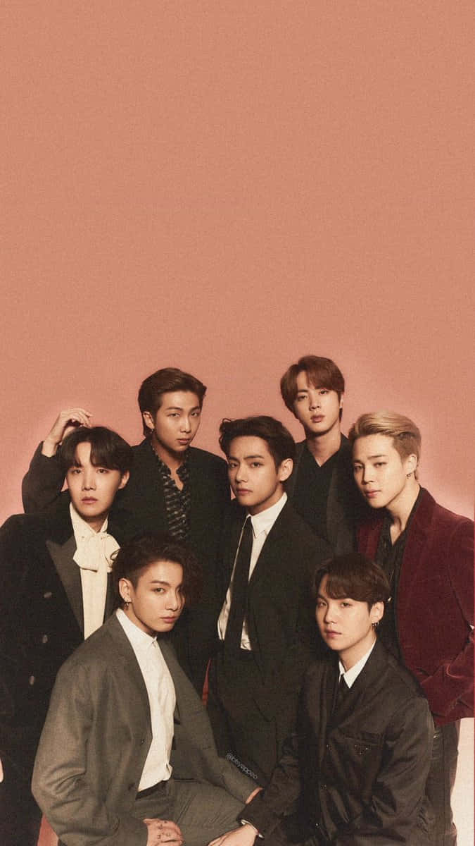 BTS 桌布 壁紙 — 七位時尚男士身著正式西裝，在純玫瑰金背景和柔和工作室燈光下自信擺姿勢。