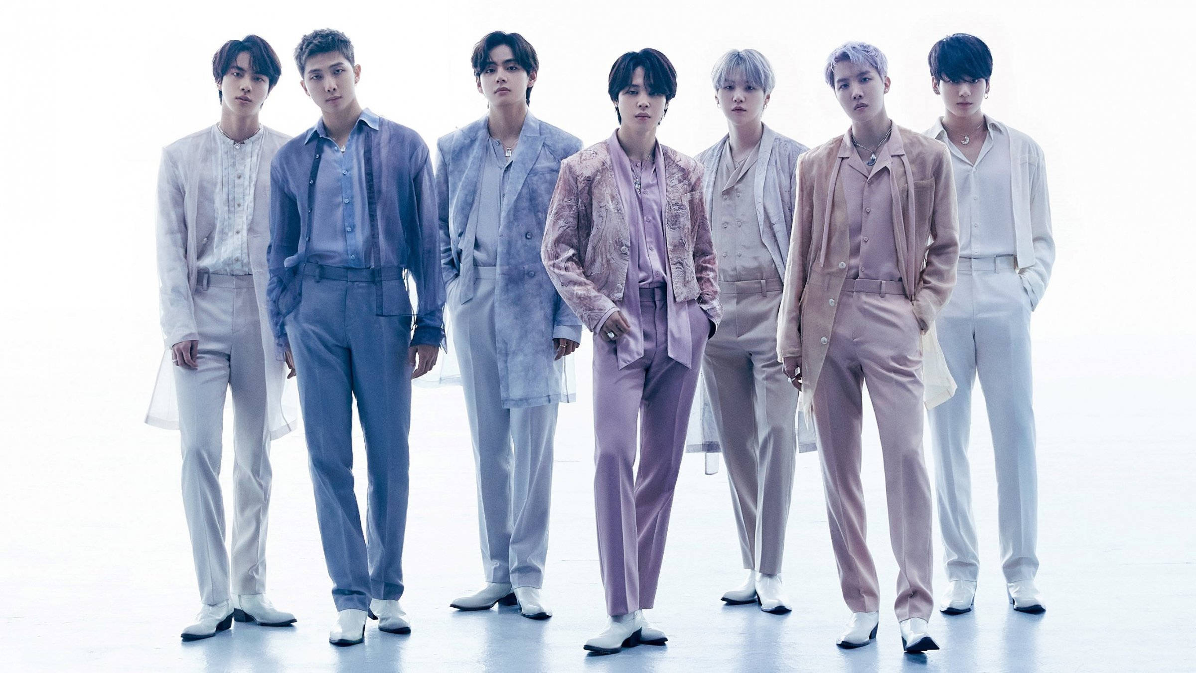 BTS 桌布 桌布 壁紙 — 七位時尚男士身著粉彩西裝，自信地站在明亮的白色攝影棚背景前。
