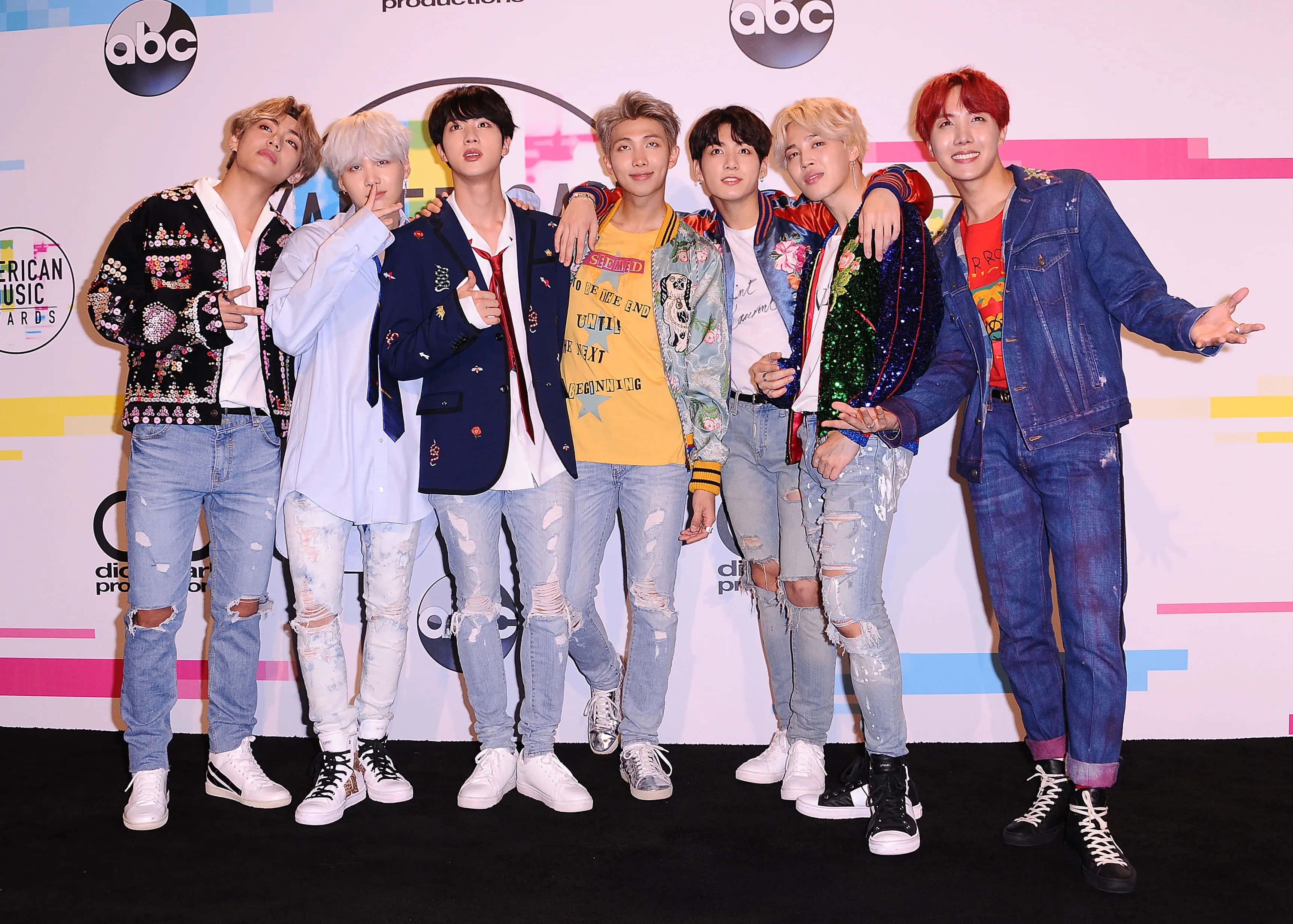 Bts Performance 桌布 壁紙 — 七位時尚的K-pop偶像在頒獎典禮的彩色舞台背景前自信地擺姿勢。