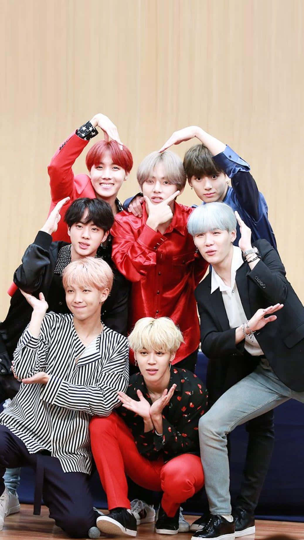 BTS 桌布 壁紙 — 七位時尚的年輕男子擁有色彩繽紛的頭髮，在木牆和明亮燈光的攝影棚中俏皮地擺姿勢。