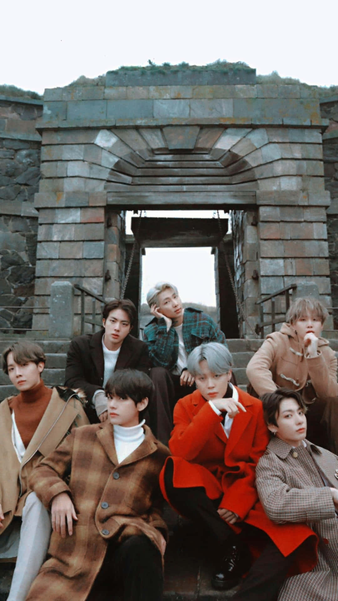 BTS 桌布 壁紙 — 七位時尚的年輕男子穿著秋季外套，在風化的石拱門下的石階上擺姿勢。