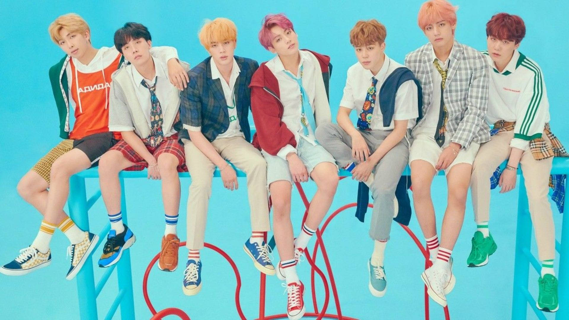 BTS 桌布 桌布 壁紙 — 七位時尚的年輕男性，擁有色彩繽紛的頭髮，隨意地坐在亮藍色的長椅上，背景是純藍色。