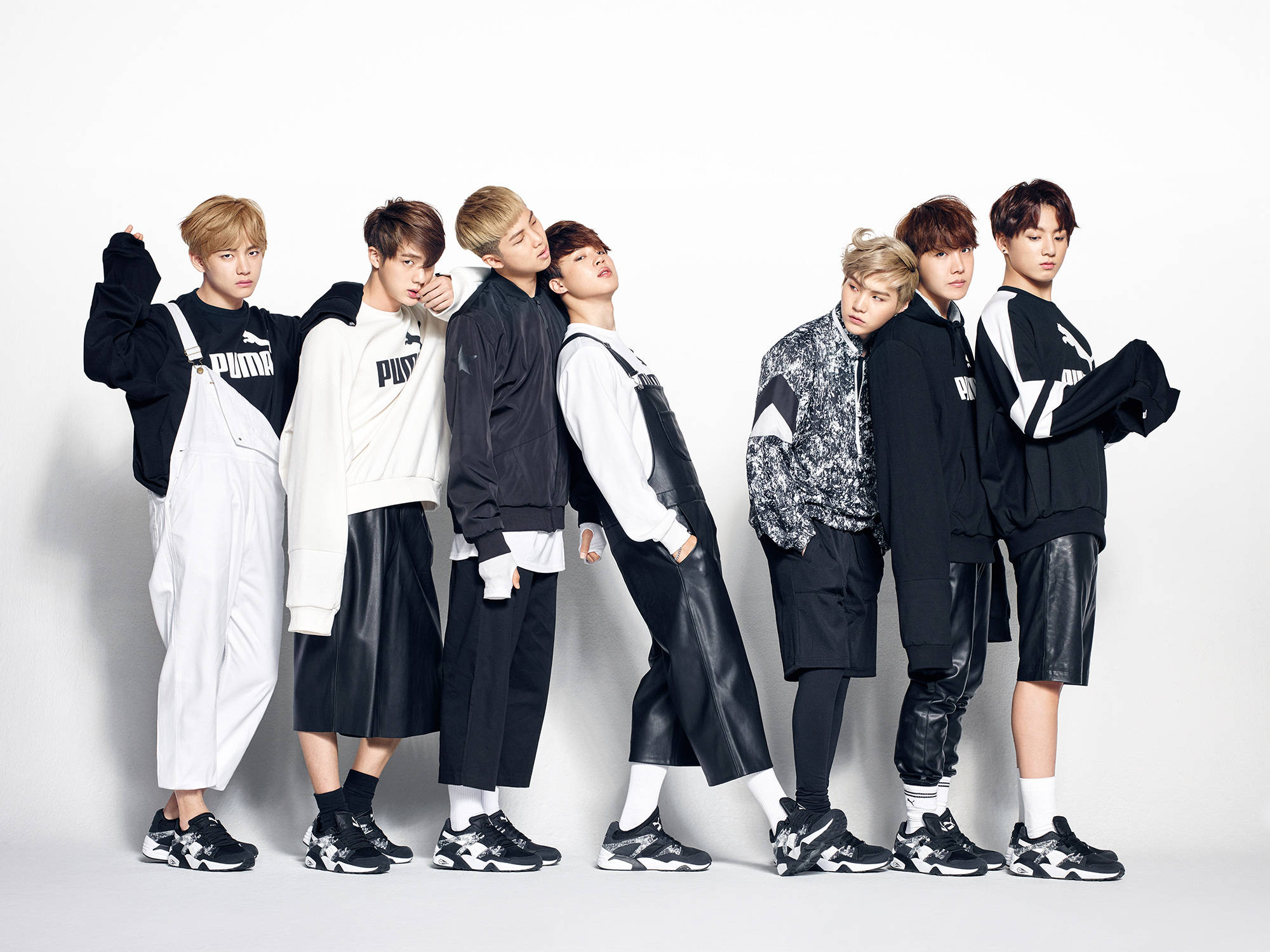 美學 BTS 桌布 壁紙 — 七位時尚的年輕男性穿著黑白Puma服裝，在純白工作室背景前自信地擺姿勢。