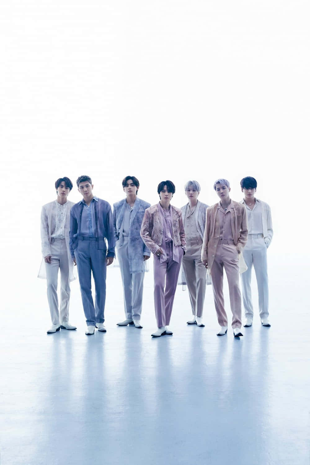 BTS 桌布 壁紙 — 七位穿著粉彩色西裝的時尚男士自信地站在明亮的白色攝影棚背景前，地板具有反射效果。