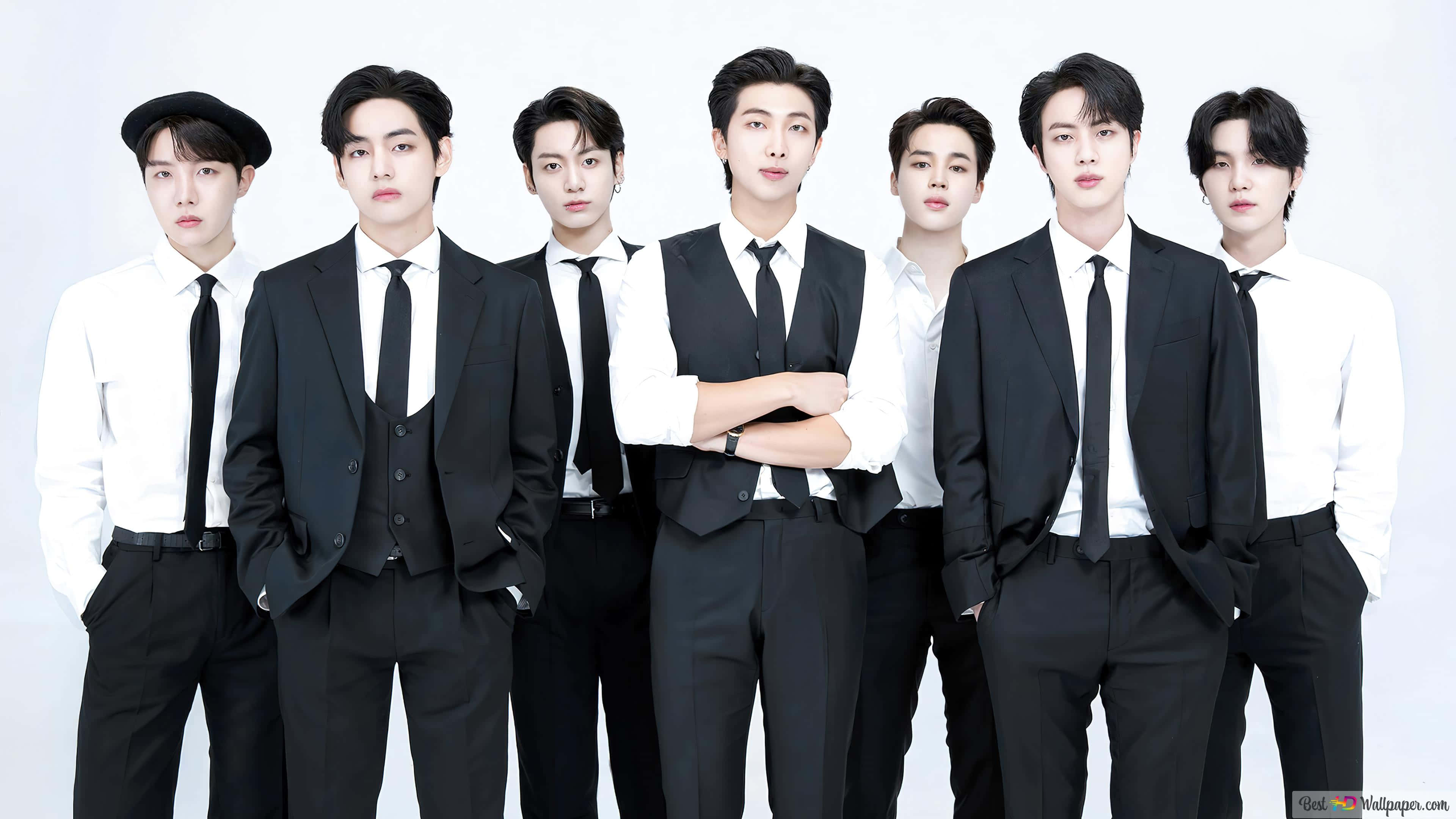 BTS 桌布 壁紙 — 七位穿著黑色西裝和白色襯衫的時尚男士在純白色背景前自信地擺姿勢。