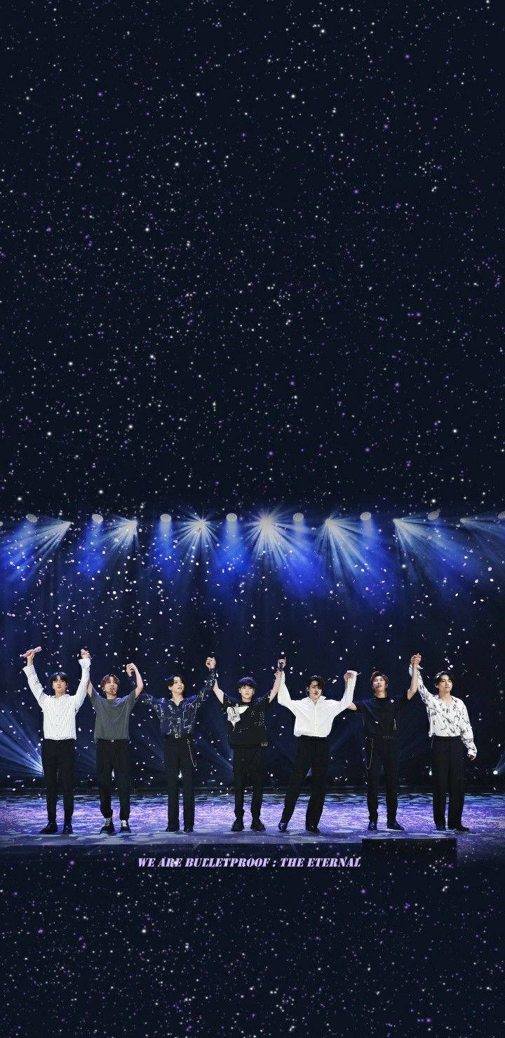 bts iPhone 桌布 壁紙 — 七位表演者在星光藍色舞台燈光下舉起手臂，文字顯示 we are bulletproof the eternal。