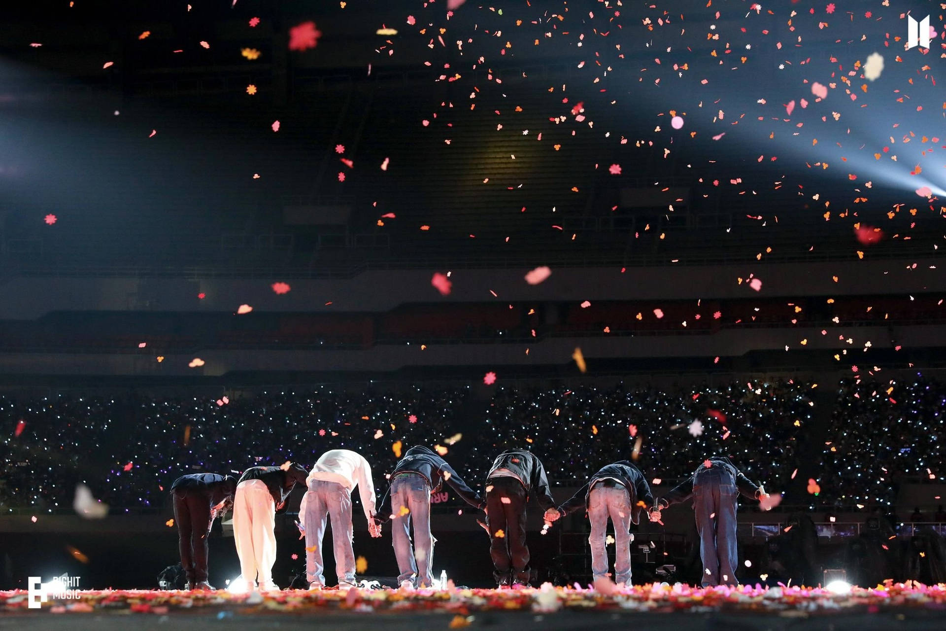 七位表演者在舞台上鞠躬，紙屑飄落，燈光閃爍。 — BTS ARMY GIF 壁紙