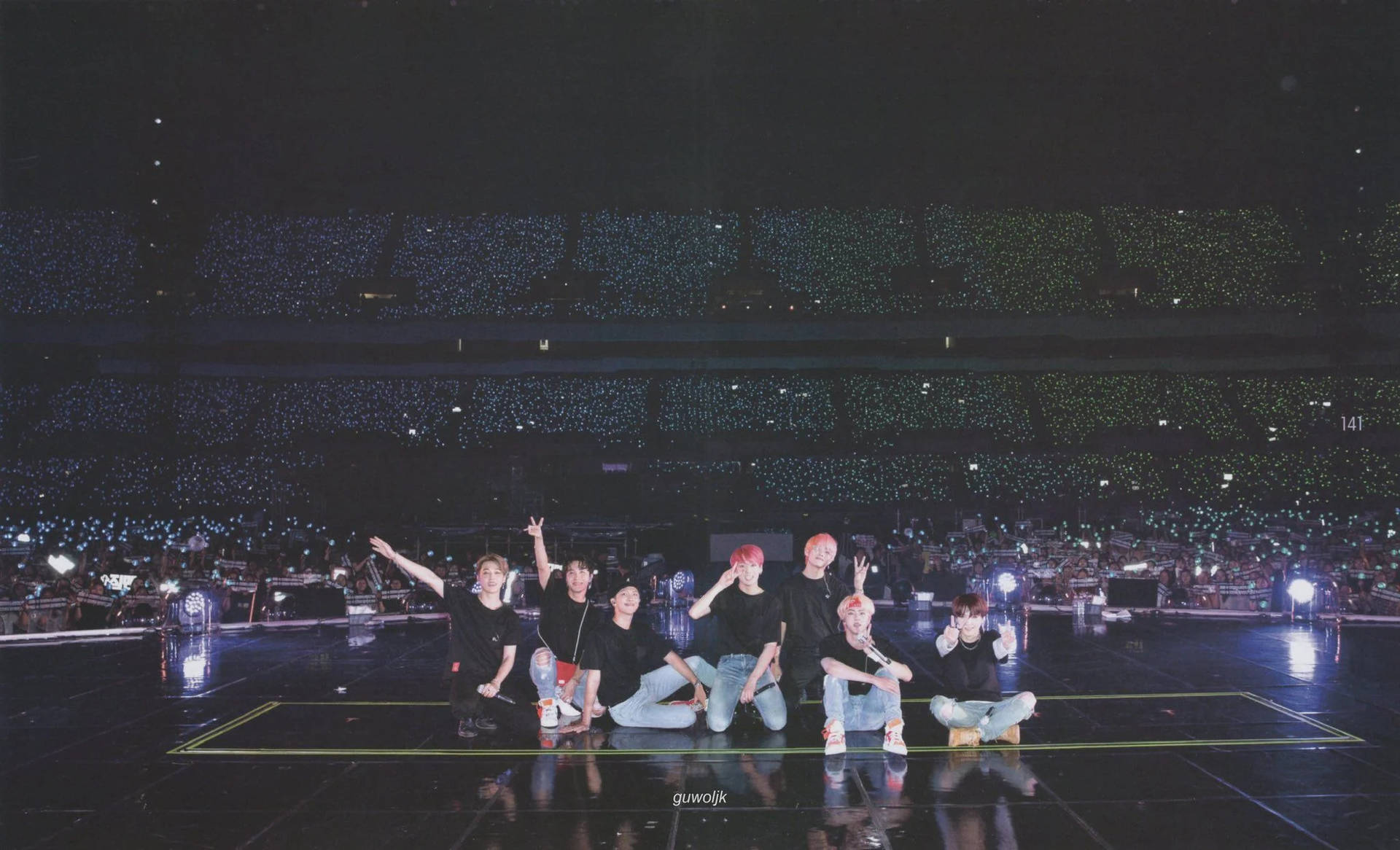 七位表演者在舞台上向藍色燈光的粉絲群揮手。 — BTS ARMY GIF 壁紙