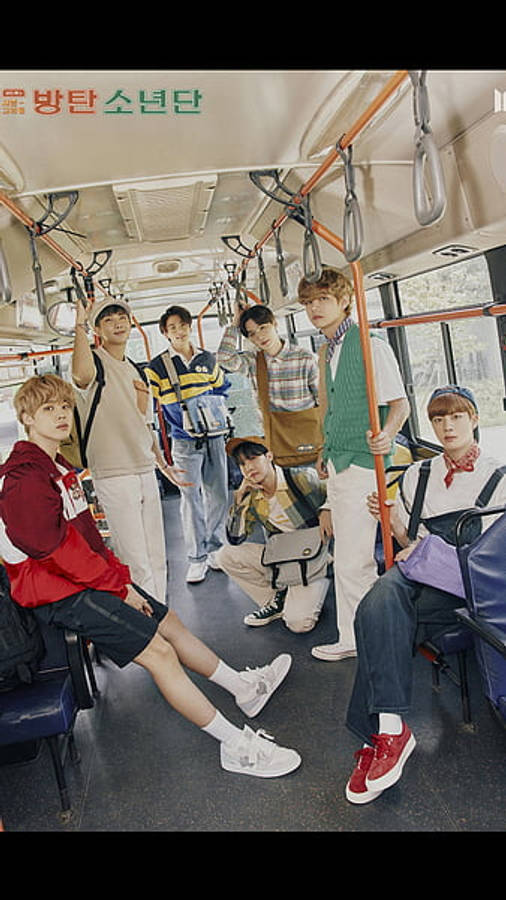 BTS 桌布 壁紙 — 七位身穿休閒街頭服的年輕男性在光線明亮的公共巴士內自信地擺姿勢，巴士有橙色扶手和藍色座椅。