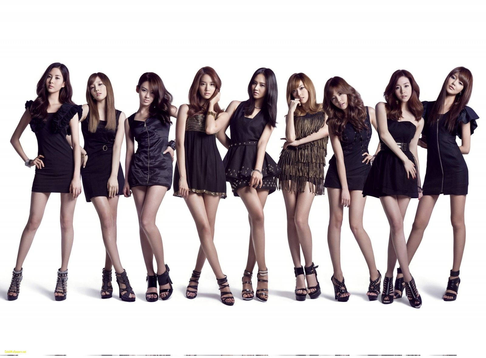 K-pop 桌布 壁紙 — 七位身穿時尚黑色連衣裙和高跟鞋的女性在純白色背景前自信地擺姿勢。