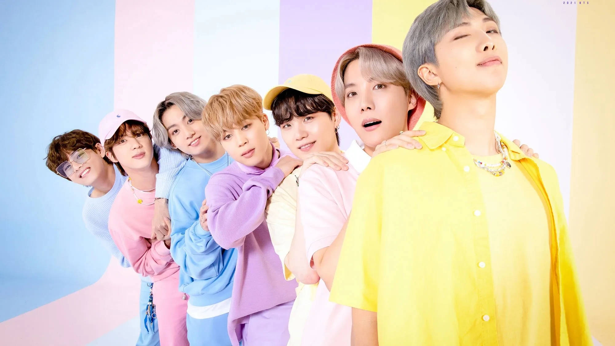 cute bts group 桌布 壁紙 — 七位身穿柔和色調服裝的年輕男性，在柔和的漸變背景前緊密地擺出姿勢，表情愉快。
