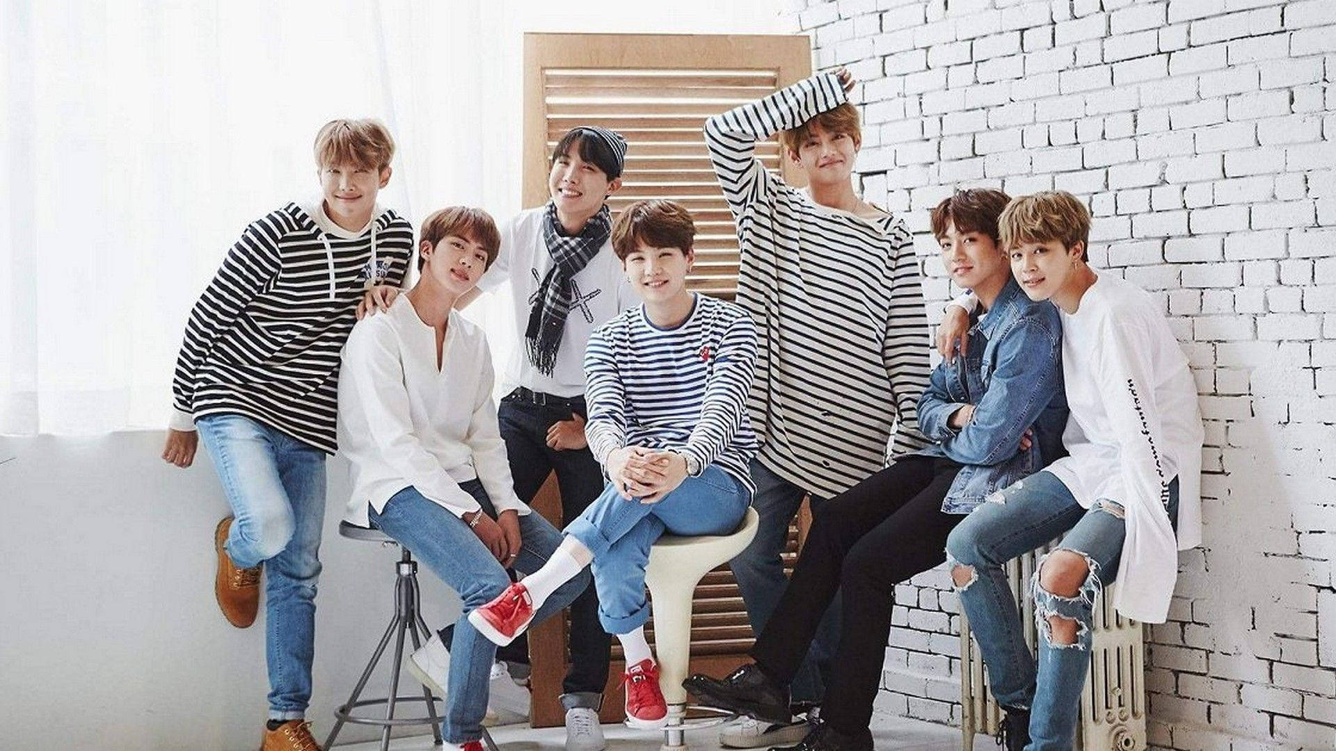 BTS 桌布 桌布 壁紙 — 七位身穿條紋和牛仔服裝的年輕男性，在柔和自然光線下，隨意地靠著白色磚牆擺姿勢。