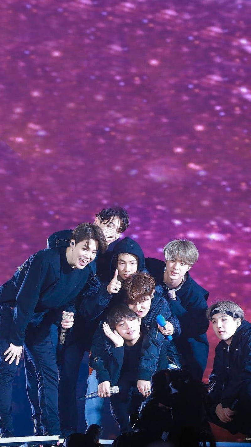 cute bts group 桌布 壁紙 — 七位身穿深色服裝的年輕男子在閃爍紫色星空的舞台上充滿活力地擺姿勢。