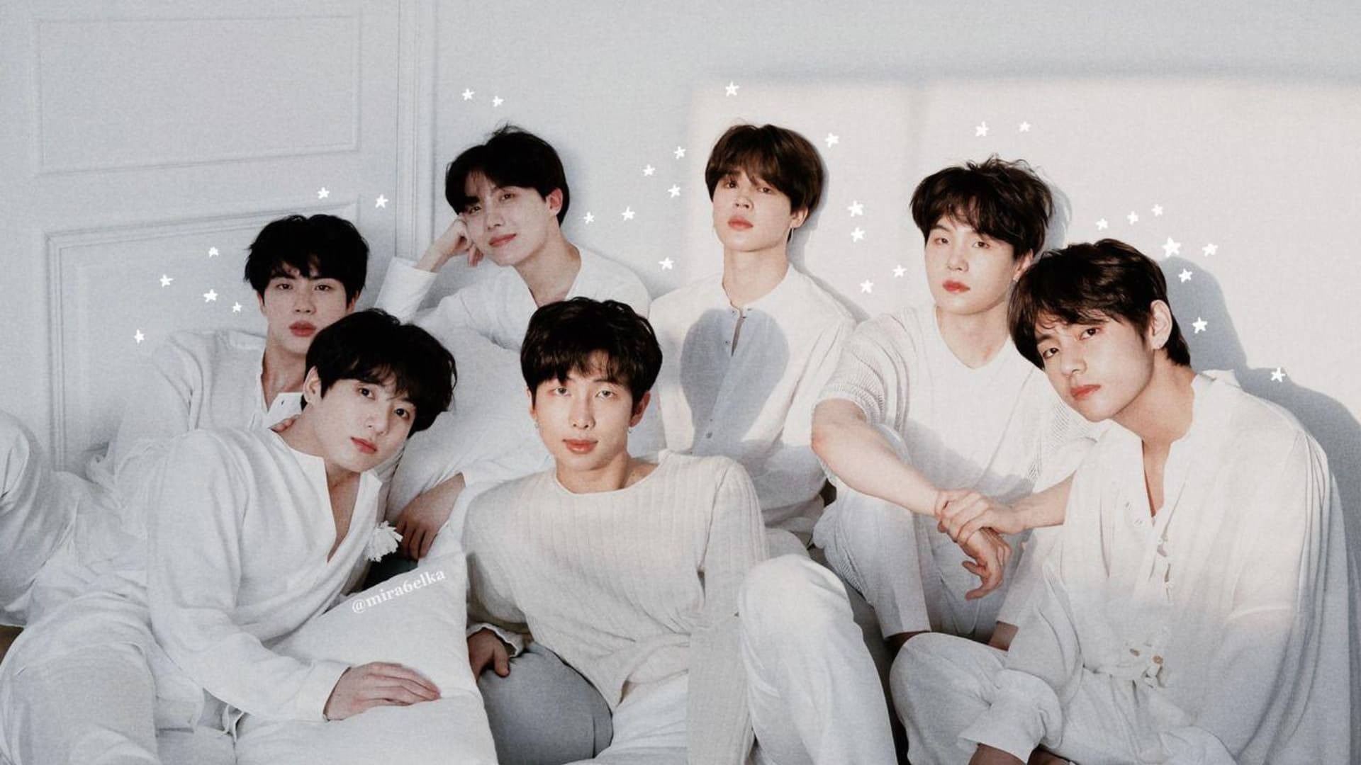 BTS 桌布 桌布 壁紙 — 七位身穿白色休閒服的年輕男性，在帶有星星圖案的白色牆壁背景下，一起在床上擺姿勢。