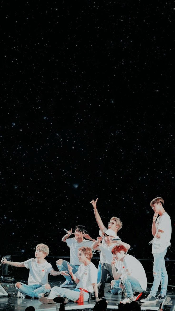 BTS 桌布 壁紙 — 七位身穿白襯衫的年輕男子在星空背景的舞台上動感擺姿勢。
