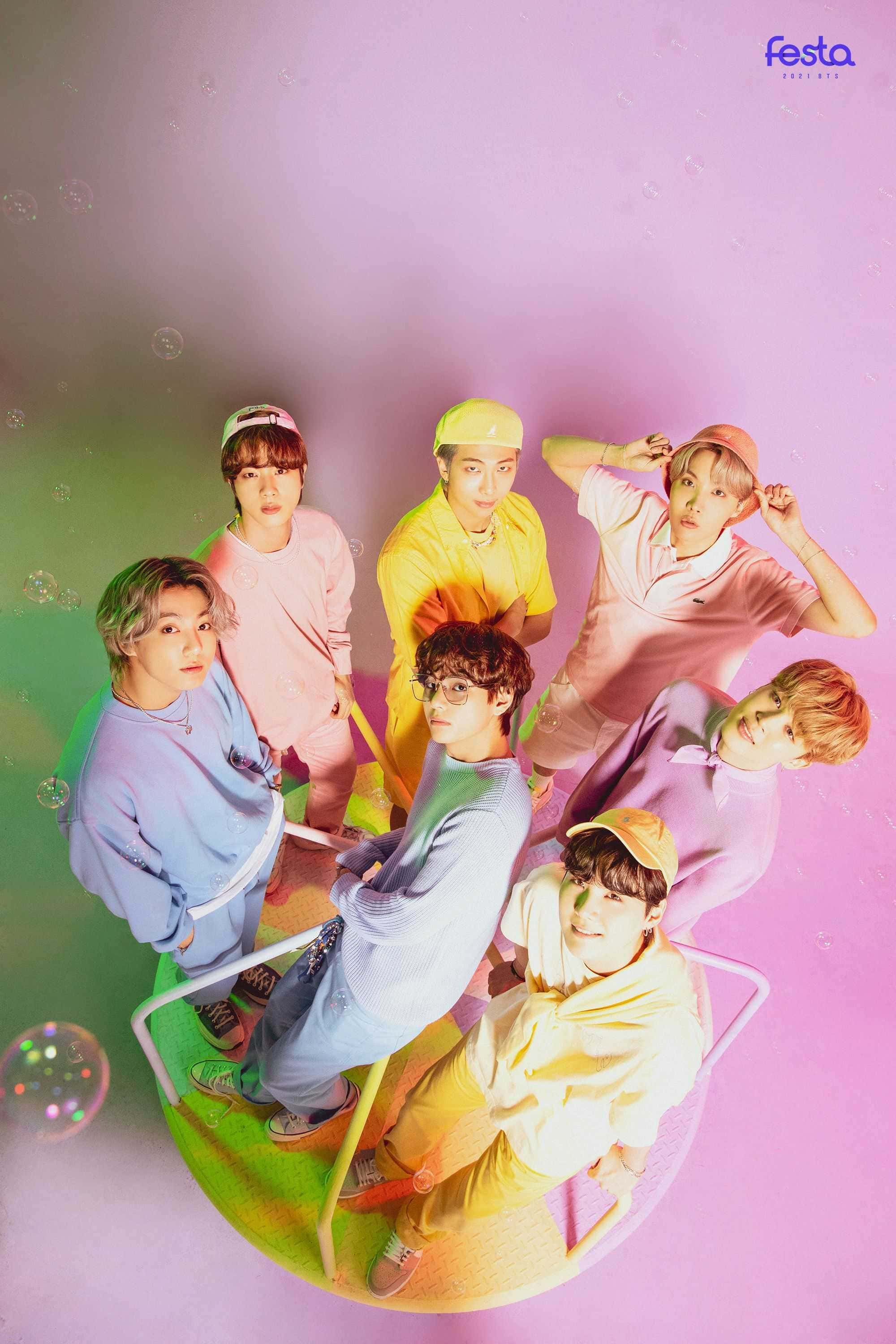BTS 桌布 壁紙 — 七位身穿粉彩服裝的年輕男子，在紫色和綠色漸變背景及漂浮氣泡的襯托下，於一張色彩繽紛的椅子上俏皮地擺姿勢。