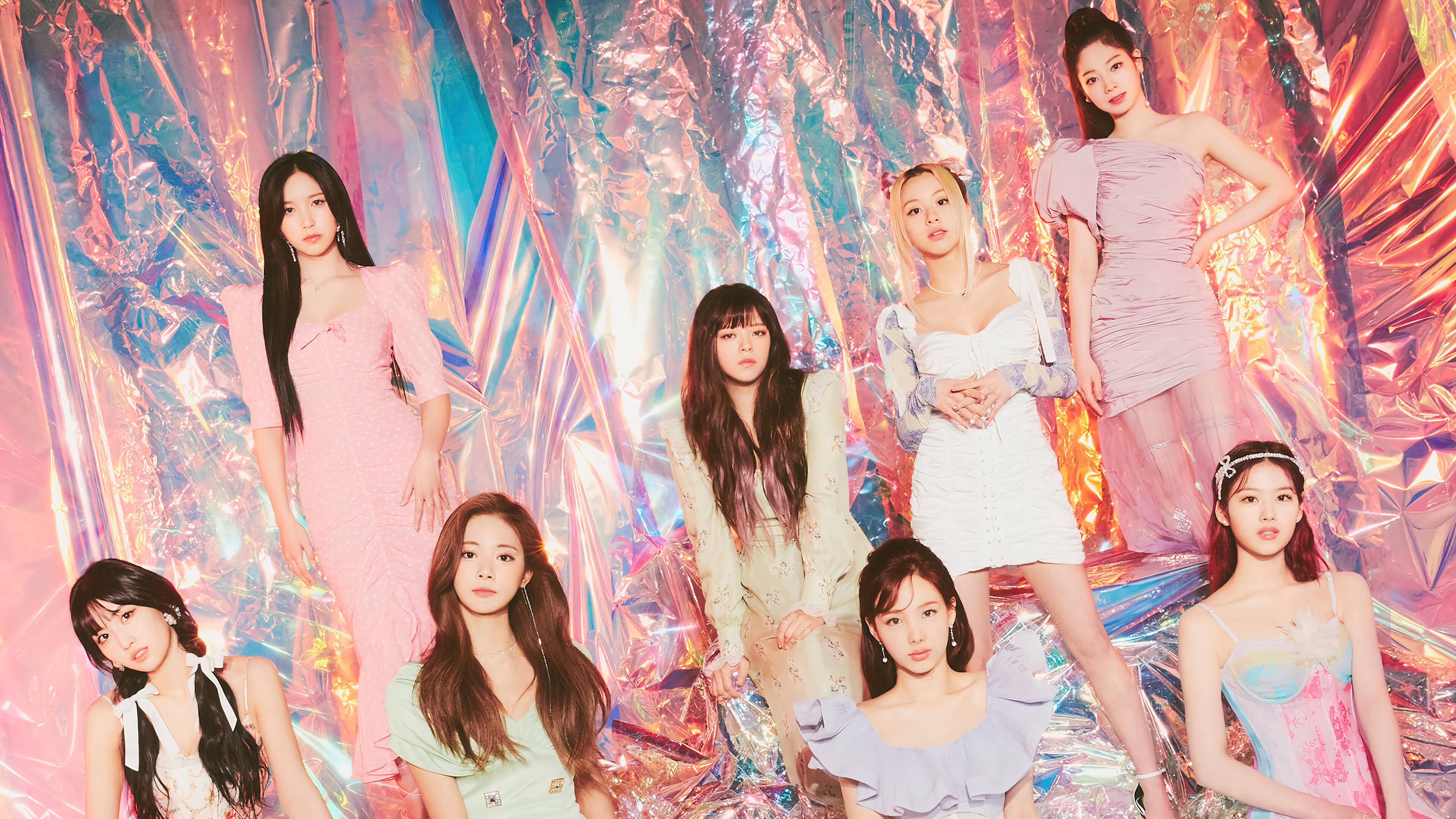 Kpop Aesthetic 桌布 壁紙 — 七位身穿粉彩連衣裙的女性在閃爍的彩虹色箔紙背景前自信地擺姿勢。