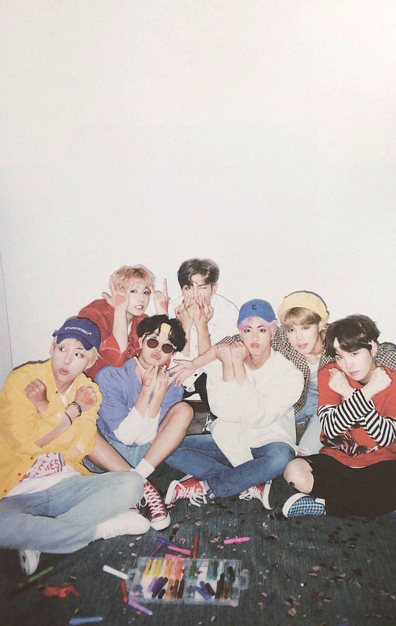 BTS 2021 桌布 壁紙 — 七位身穿色彩繽紛休閒服的年輕男子，在散落蠟筆的地板上，對著純白牆壁頑皮地擺姿勢。