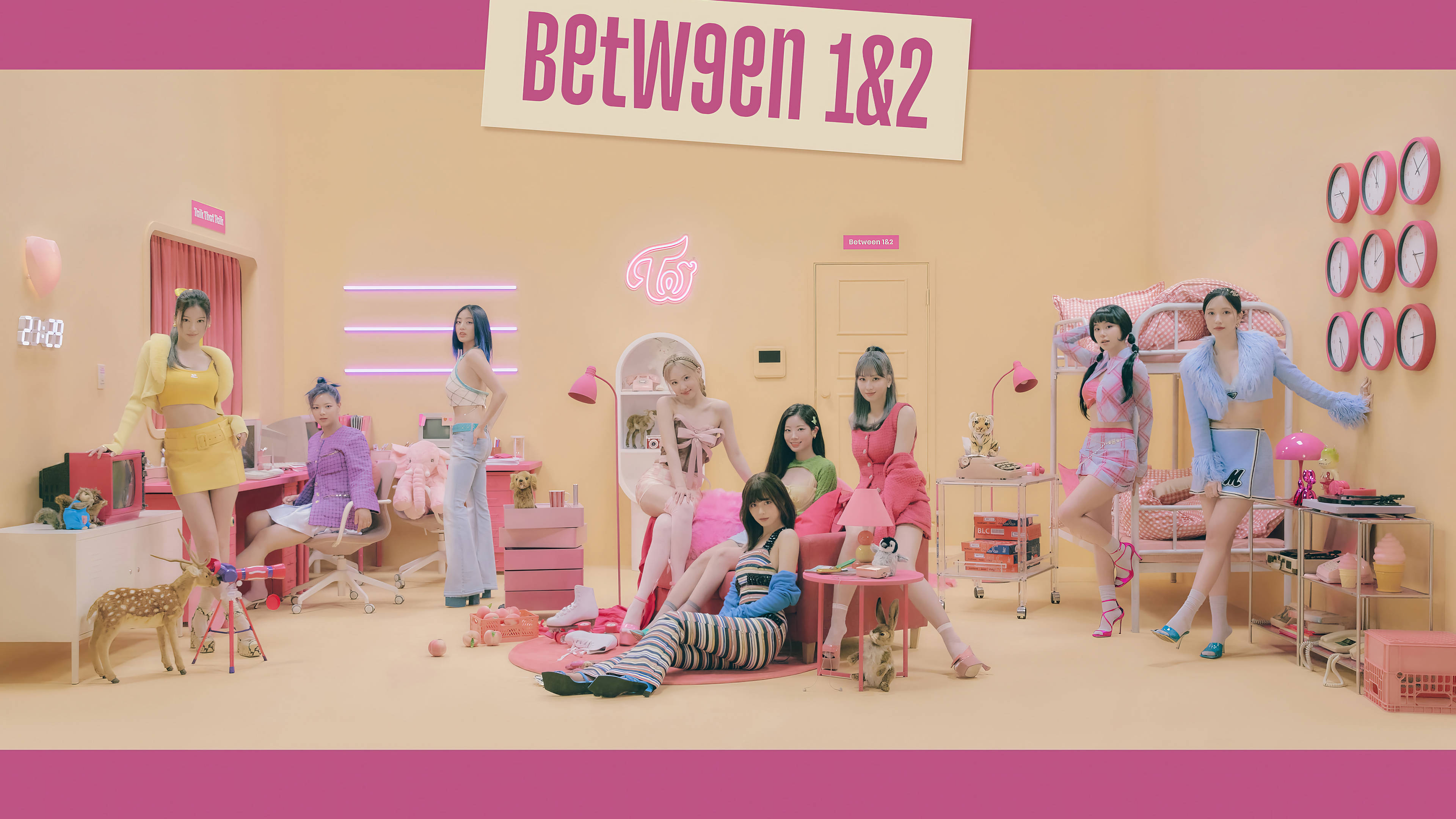 Kpop Aesthetic 桌布 壁紙 — 七位身穿色彩繽紛服裝的女性在一個充滿時鐘和家具的粉彩粉紅和黃色房間中俏皮地擺姿勢。