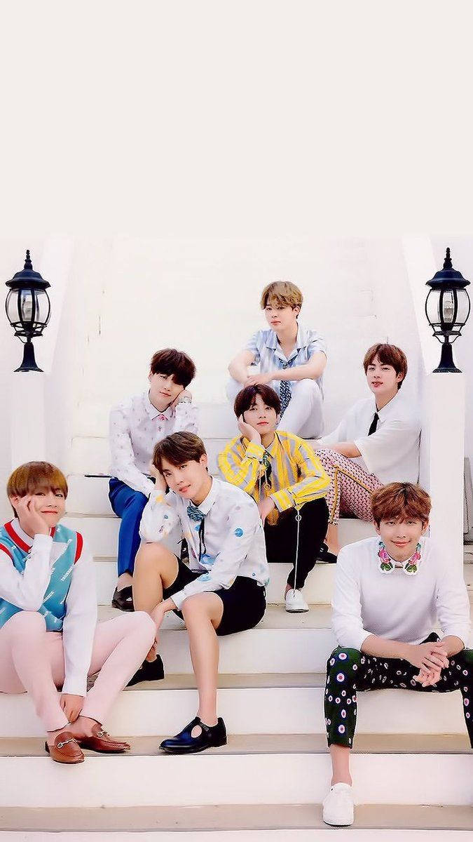 BTS 桌布 壁紙 — 七位身穿色彩繽紛服裝的年輕男性在明亮的日光下，在兩旁有黑色燈籠的白色石階上隨意擺姿勢。