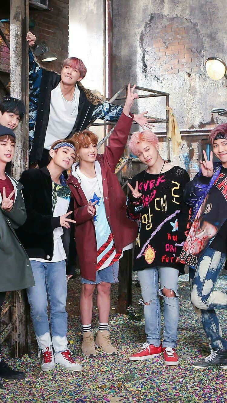 BTS 桌布 壁紙 — 七位身穿色彩繽紛街頭服的年輕男子，在骯髒的城市小巷中，於五彩紙屑中愉快地擺姿勢。