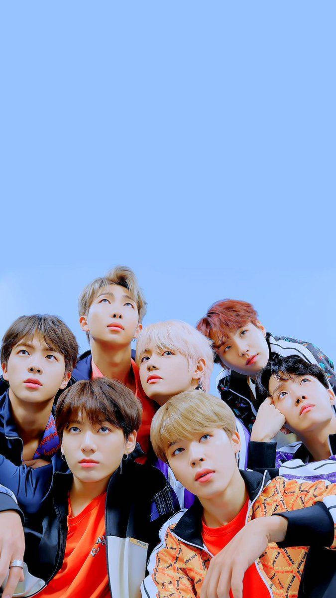 BTS 鎖定螢幕 桌布 壁紙 — 七位身穿色彩繽紛街頭服飾的年輕男性，在晴朗的藍天下向上凝視，構成動態的群像照。