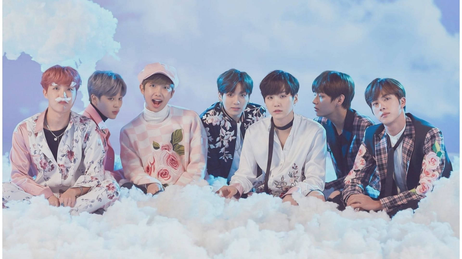 BTS 桌布 桌布 壁紙 — 七位身穿花卉服裝的年輕男子在柔軟的藍天背景下，於蓬鬆的白雲上擺姿勢。