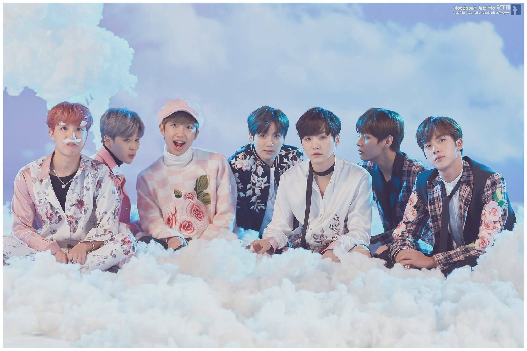 bts 2021 desktop 桌布 壁紙 — 七位身穿花卉服裝的年輕男性坐在蓬鬆的白雲上，背景是柔和的藍天，帶有戲劇性的燈光效果。