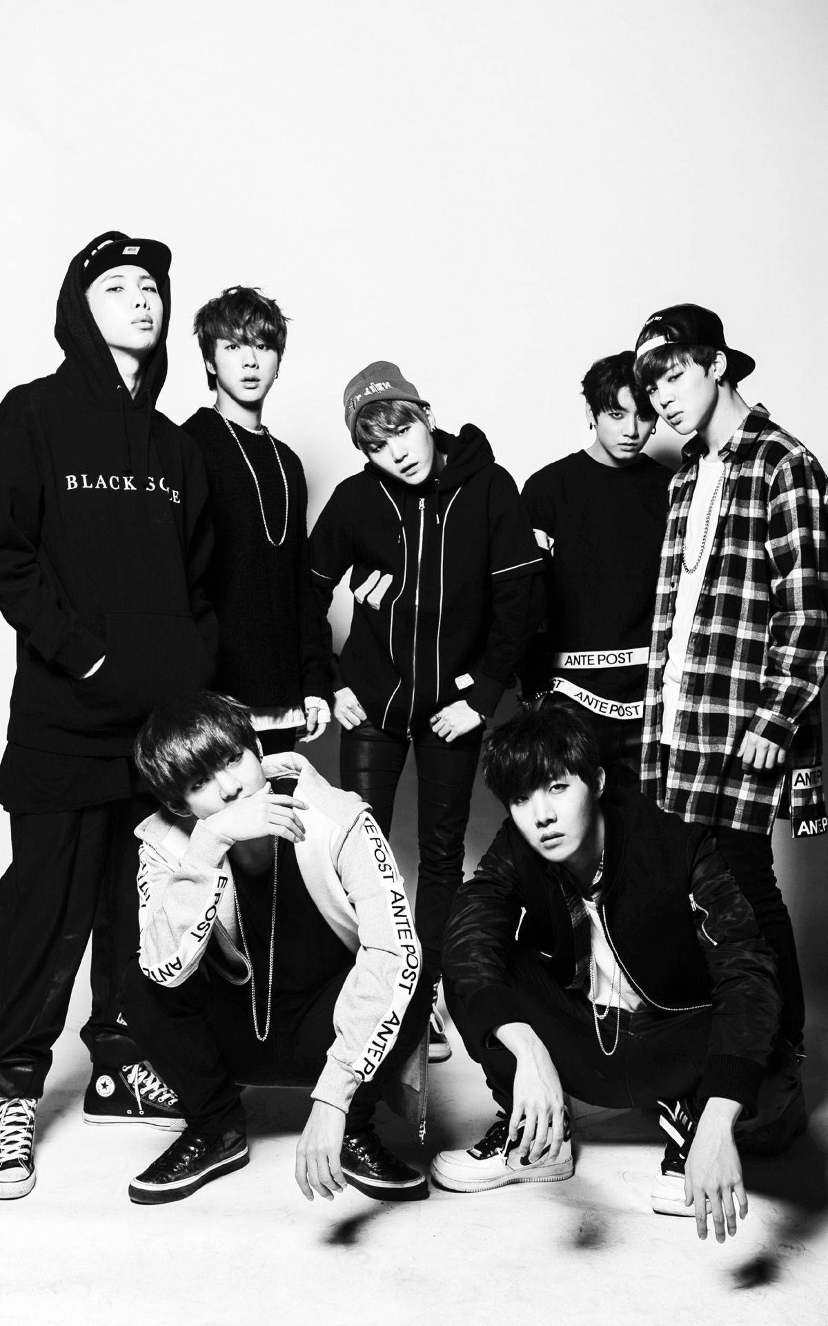 BTS 桌布 壁紙 — 七位身穿街頭服飾的年輕男性在純白背景前自信地擺姿勢，呈現高對比度的黑白攝影棚拍攝效果。