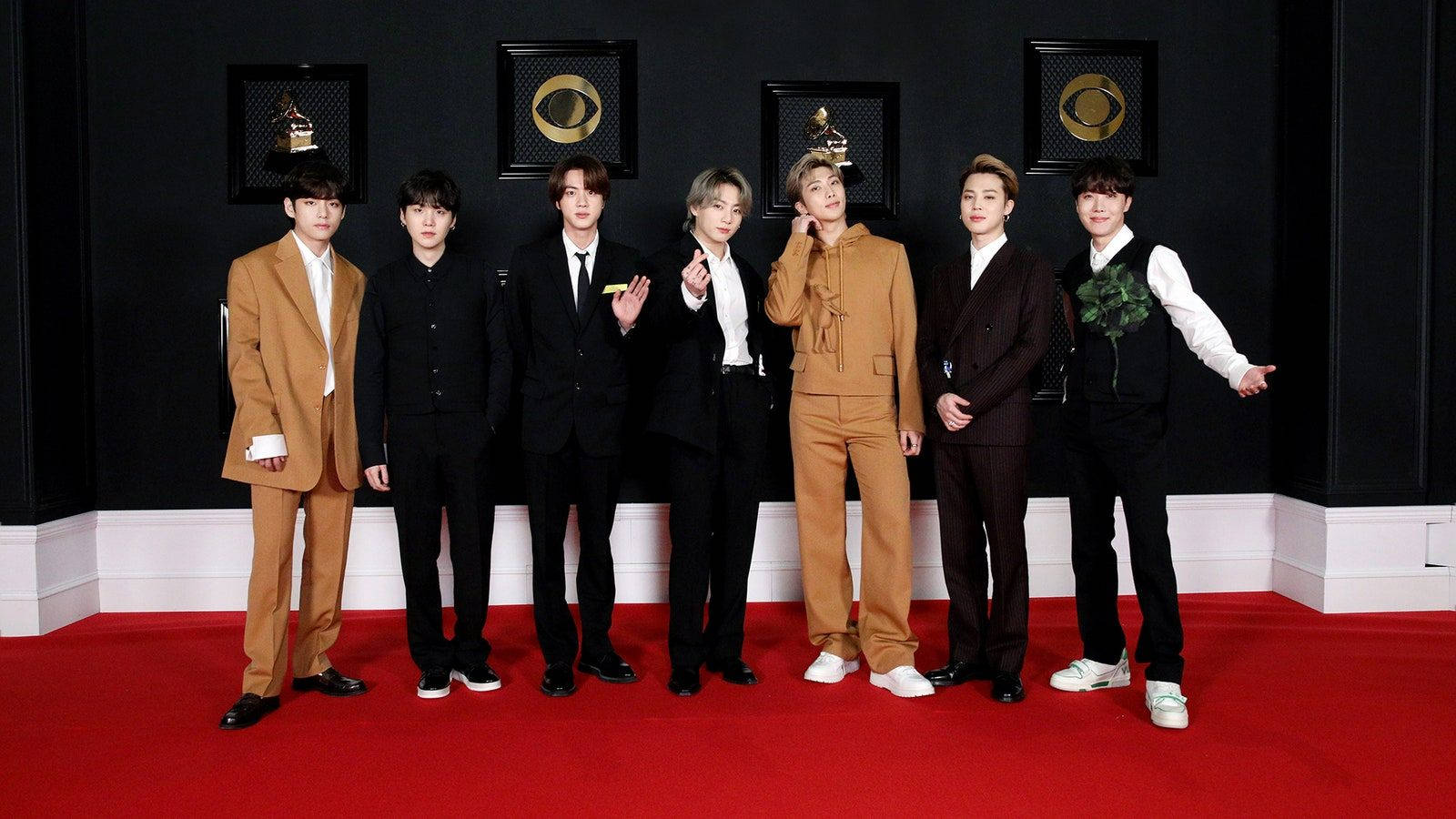 BTS 2021 桌布 壁紙 — 七位身穿西裝的時尚男士在紅地毯上自信地擺姿勢，背景是裝飾著葛萊美獎項的黑色牆壁。