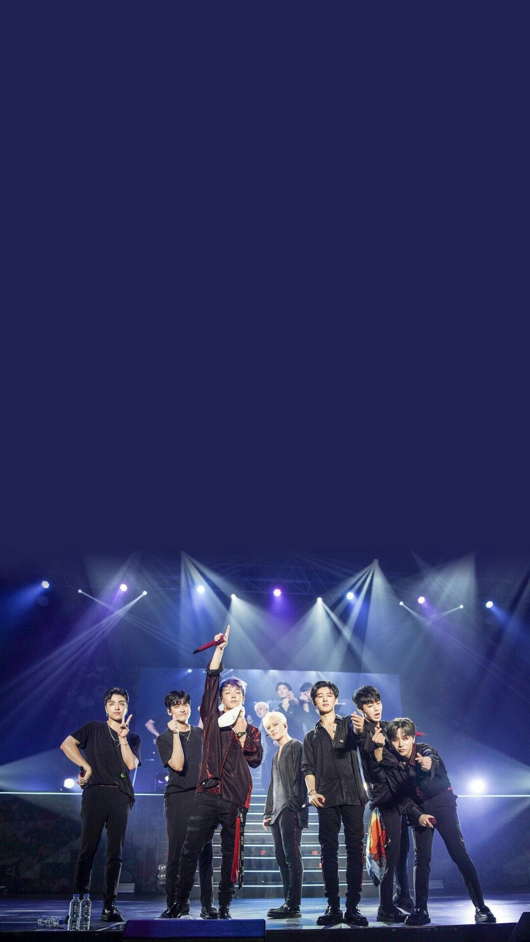 Ikon 桌布 壁紙 — 七位身穿黑色服裝的男性表演者在黑暗的演唱會舞台上，在明亮的舞台燈光下動態擺姿勢。