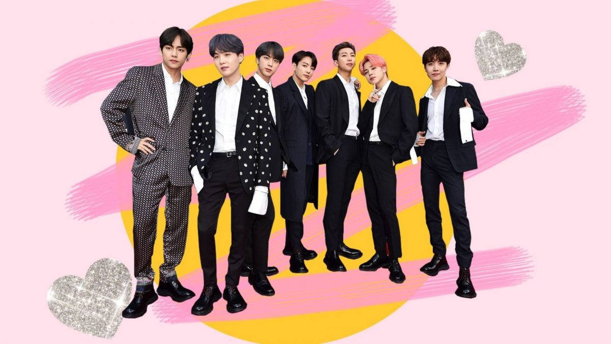 bts group cute 桌布 壁紙 — 七位身穿黑色西裝的時尚男士在充滿活力的粉紅色和黃色抽象背景前自信地擺姿勢，背景中閃爍著心形圖案。