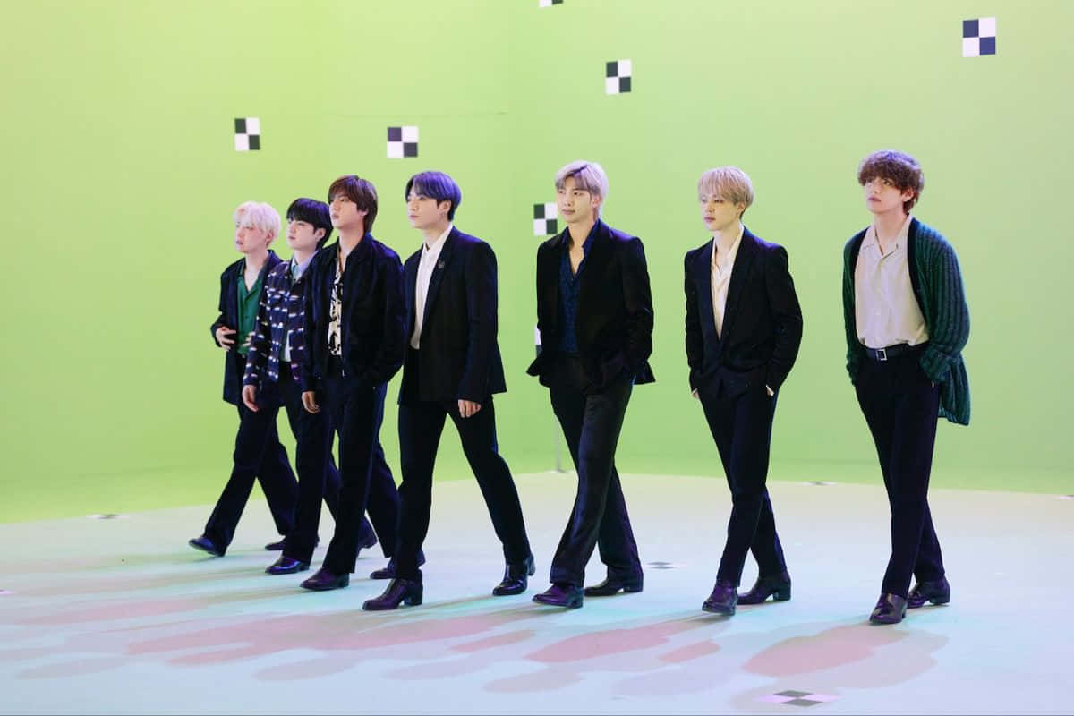 Bts Endorsements 桌布 壁紙 — 七位身穿黑色西裝的時尚男士自信地走過充滿活力的綠色攝影棚地板，牆上帶有幾何裝飾。